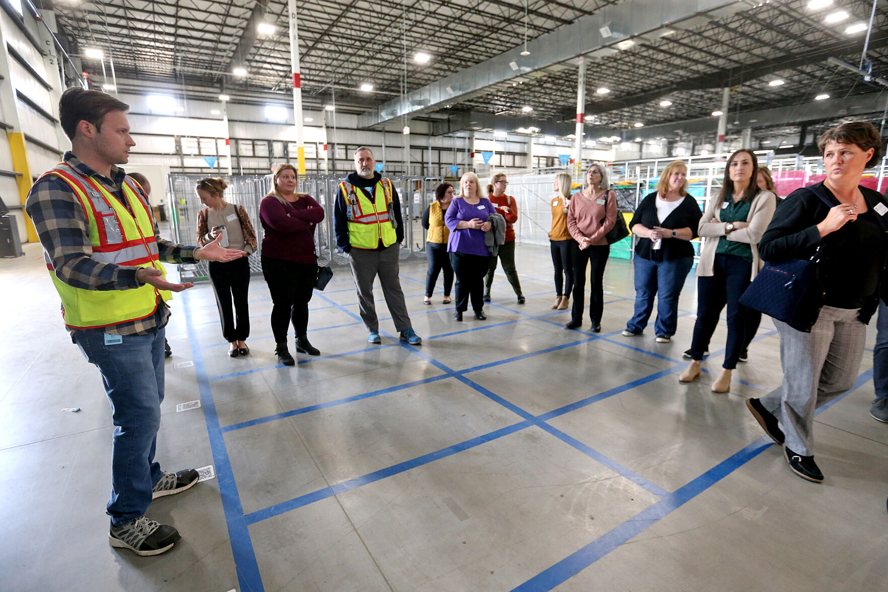 Max Flynn (far left), a manager at Amazon, gives a tour of the facility in Dubuque on Thursday, Oct. 20, 2022. Iowa Vocational Rehabilitation Services hosted a tour of local businesses that hire people with disabilities as part of National Disability Employment Awareness Month.    PHOTO CREDIT: JESSICA REILLY