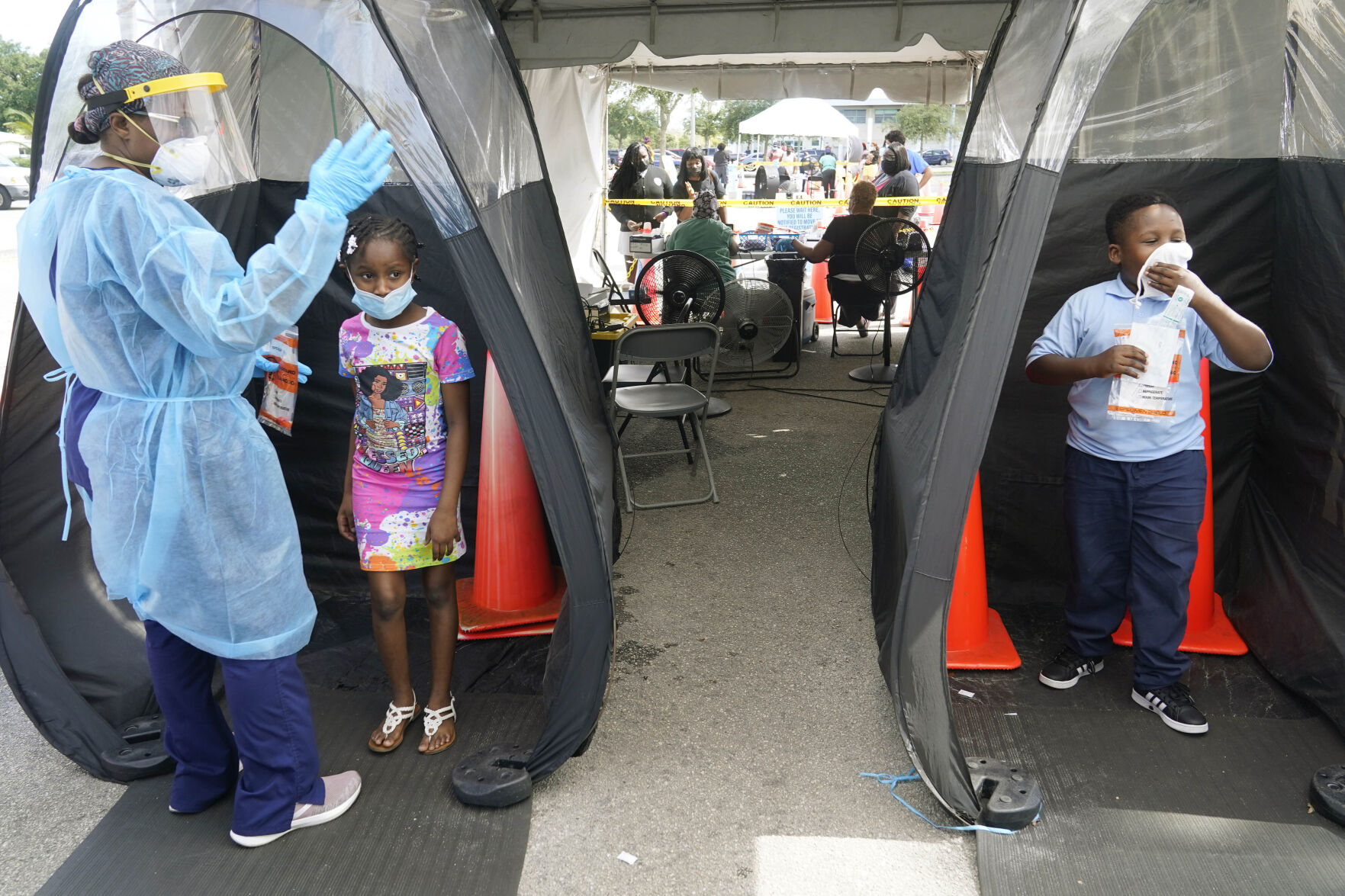 <p>FILE - Wenderson Cerisene, 7, right, and his sister Dorah, 9, wait to be tested for COVID-19, Aug. 31, 2021, in North Miami, Fla. In interviews with The Associated Press, close to 50 school leaders, teachers, parents and health officials reflected on decisions to keep students in extended online learning, especially during the spring semester of 2021. (AP Photo/Marta Lavandier, File)</p>   PHOTO CREDIT: Marta Lavandier - staff, AP