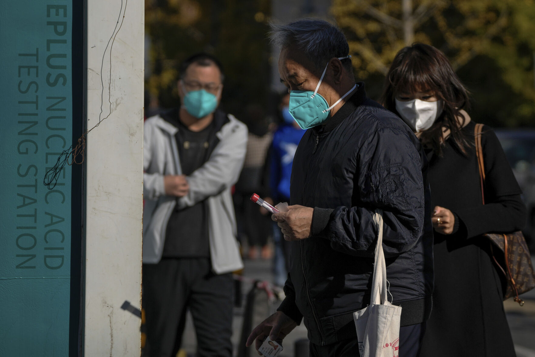<p>A man wearing a face mask holds his testing tube as masked residents line up for their routine COVID-19 throat swabs at a coronavirus testing site in Beijing, Monday, Oct. 31, 2022. (AP Photo/Andy Wong)</p>   PHOTO CREDIT: Andy Wong - staff, AP