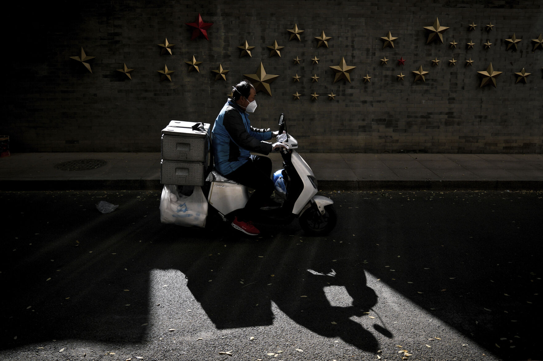 <p>A food delivery rider wearing a face mask rides past communist symbol of stars on display outside a restaurant in Beijing, Monday, Oct. 31, 2022. (AP Photo/Andy Wong)</p>   PHOTO CREDIT: Andy Wong - staff, AP