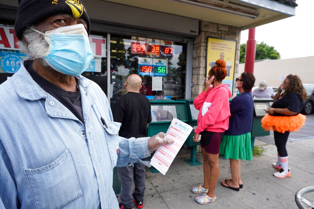 Philip Smith, wears a face mask and gloves as he lines up to purchase his lottery tickets for the Powerball lottery at the Blue Bird Liquor store in Hawthorne, Calif. There were no big treats from the Halloween night Powerball drawing, as none of the tickets sold matched all six numbers. The lack of a winner means the next drawing Wednesday night will be for a massive $1.2 billion jackpot.    PHOTO CREDIT: Damian Dovarganes