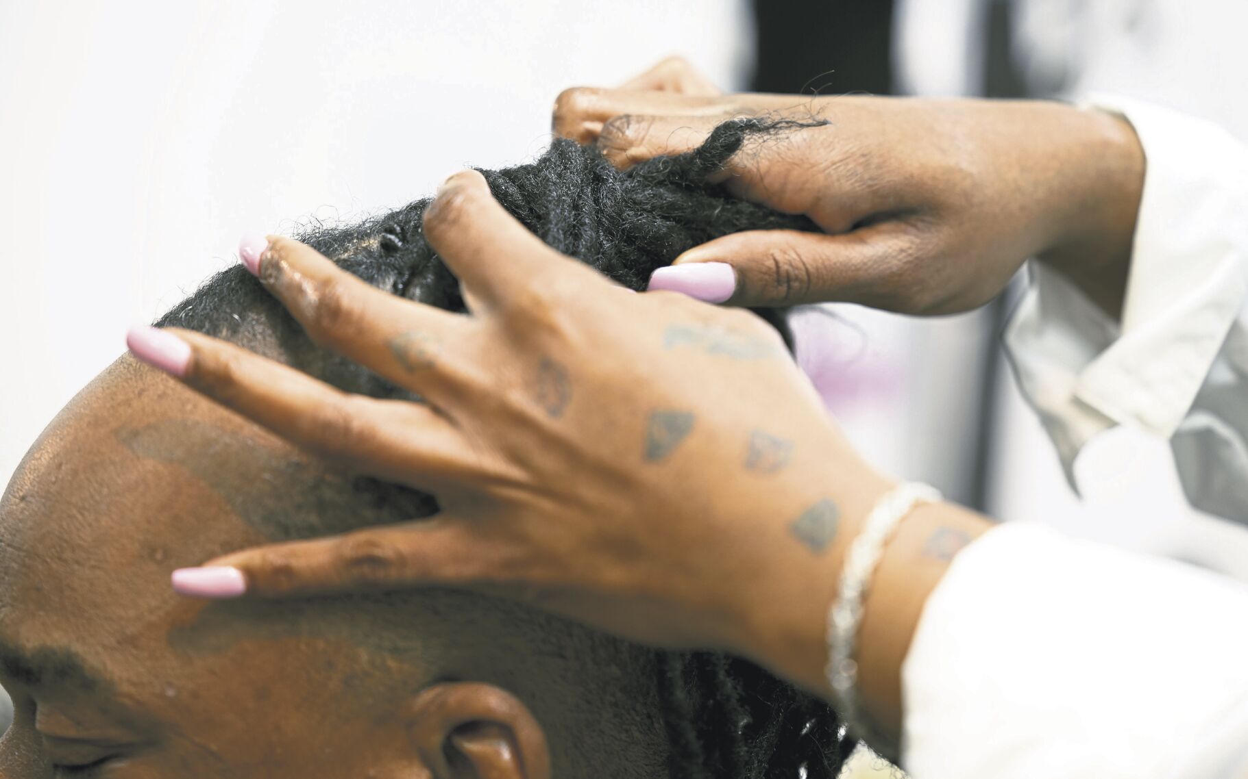 Shamika Rainer works on the hair of Willie Dunbar at Luxurious Hair Spa.    PHOTO CREDIT: Stephen Gassman