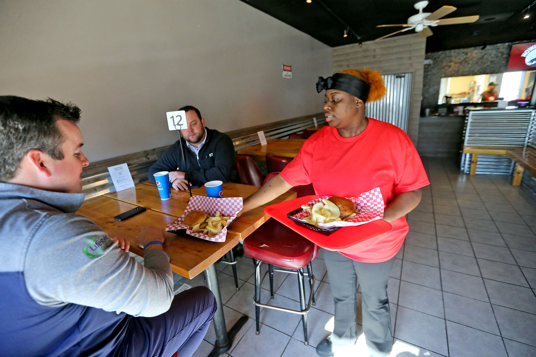 Dawneacia Arnold brings an order to Austin Vogt (far left) and Alex Gaul, both of Dubuque, at Howling BBQ in Dubuque on Wednesday, Nov. 9, 2022.    PHOTO CREDIT: JESSICA REILLY