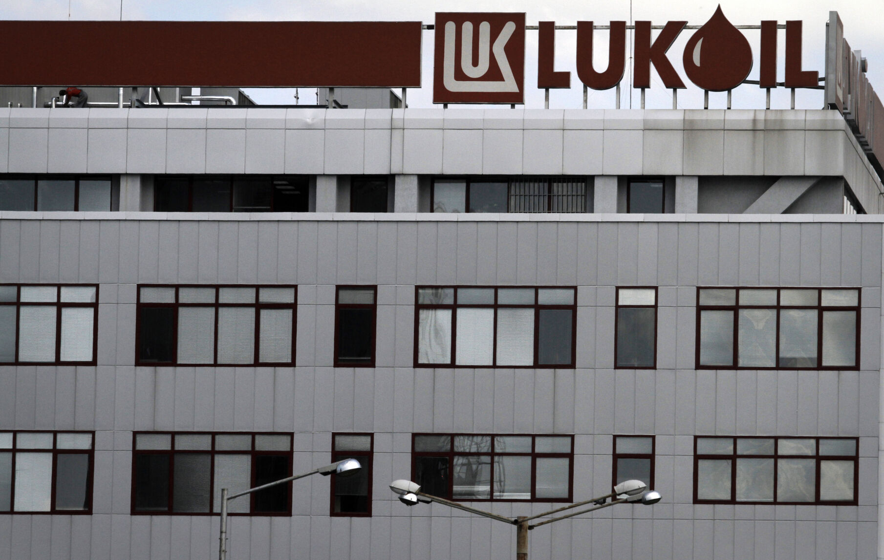 <p>FILE - A worker, top left, works on the roof of the Lukoil headquarters in the Bulgarian capital Sofia, July 27, 2011. Bulgaria will allow Lukoil, a Black Sea refinery owned by a Russian oil company, to keep operating and exporting oil products to the European Union until the end of 2024 despite warnings by Brussels that it is against the bloc’s sanctions. (AP Photo/Valentina Petrova, File)</p>   PHOTO CREDIT: Valentina Petrova - stringer, AP