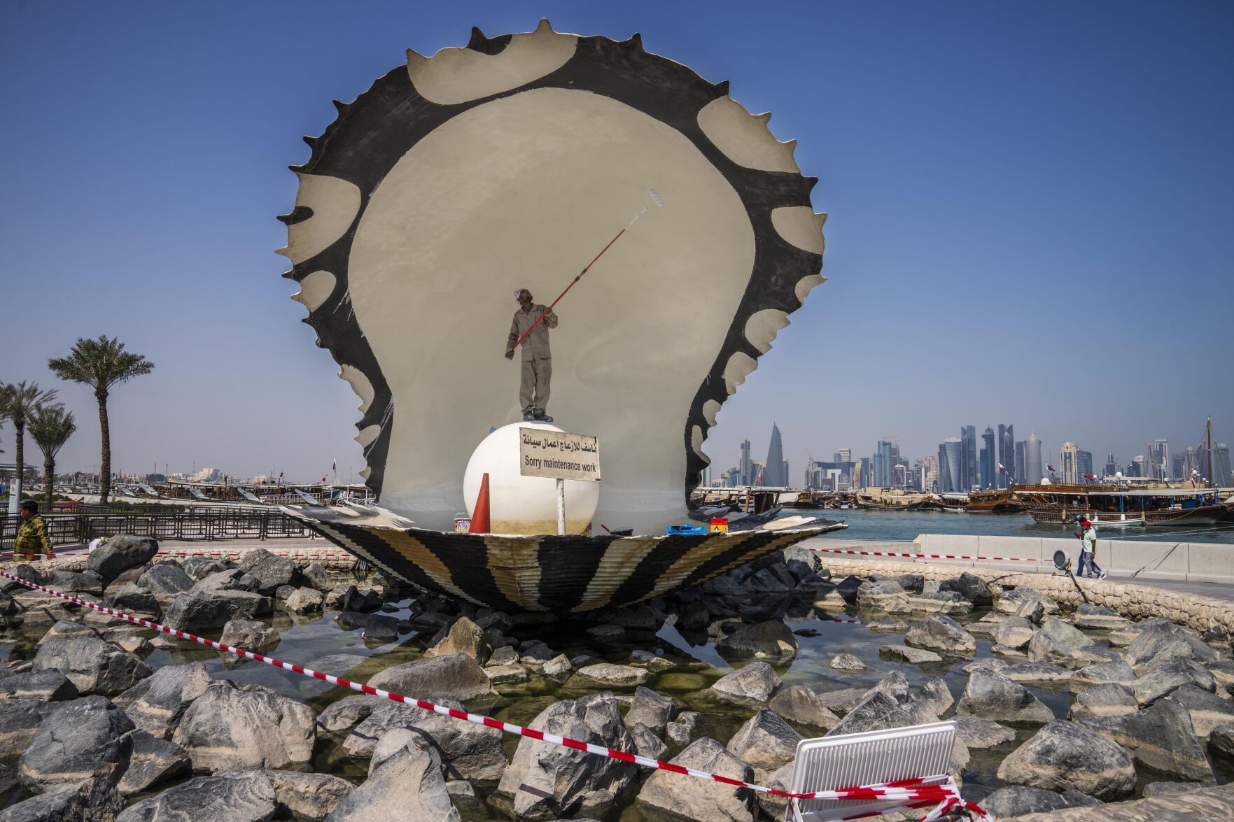 <p>A migrant laborer paints The Pearl Monument, a sculpture depicting an open oyster shell with running water, on the corniche, overlooking the skyline of Doha, Qatar, Wednesday, Oct. 19, 2022. One of the world’s biggest sporting events has thrown an uncomfortable spotlight on Qatar’s labor system, which links workers’ visas to employers and keeps wages low for workers toiling in difficult conditions. (AP Photo/Nariman El-Mofty)</p>   PHOTO CREDIT: Nariman El-Mofty 