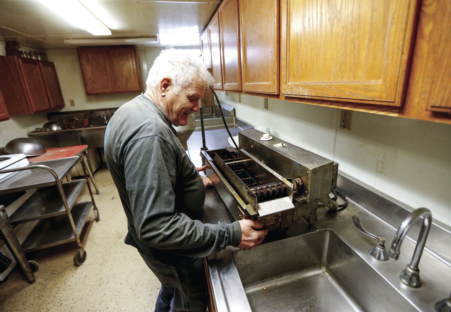 Walter Hammerand of Fennimore, Wis., cleans his donut maker that he uses to make fresh doughnuts at the farmers market.    PHOTO CREDIT: Dave Kettering
Telegraph Herald