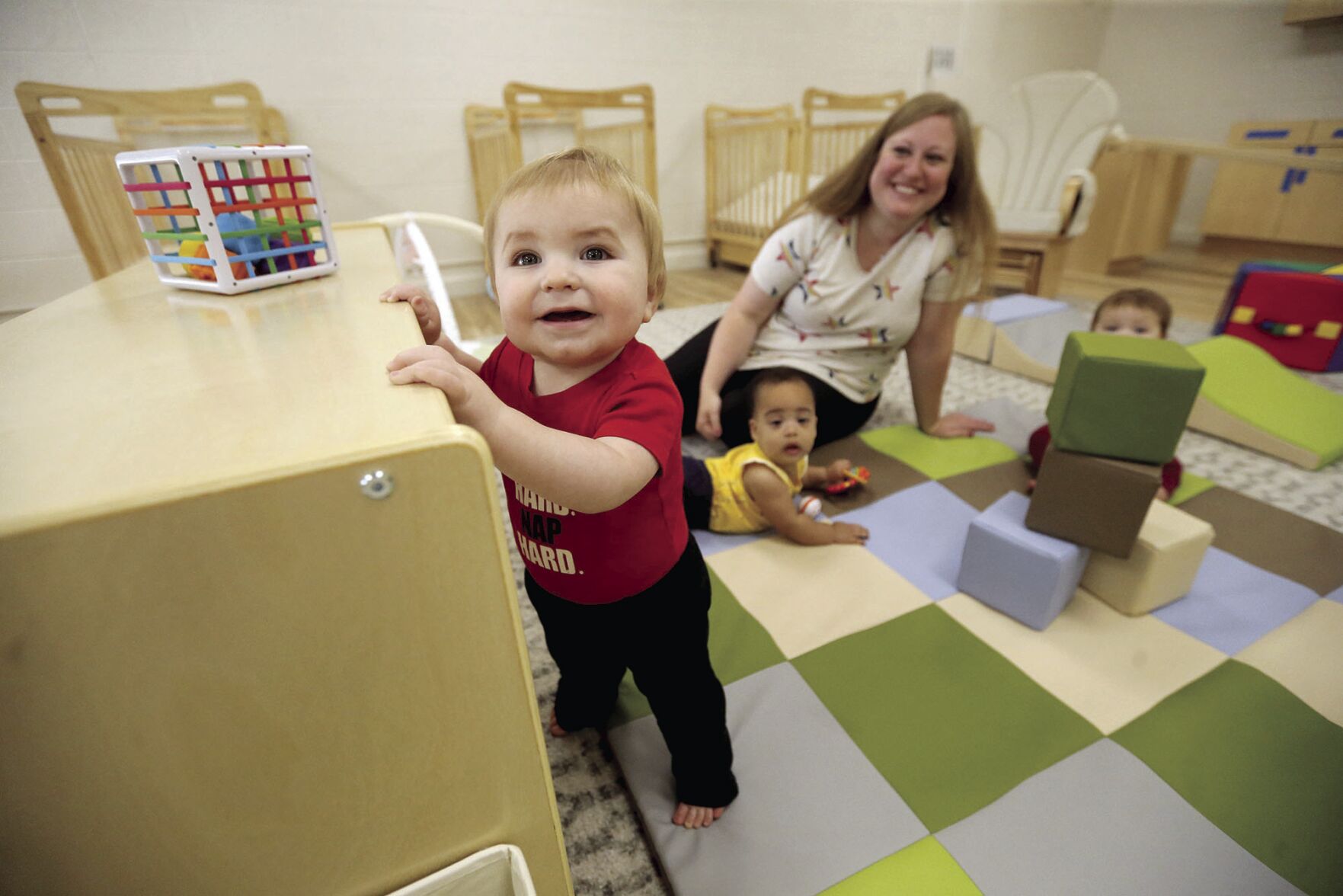 Sheena Gillen, lead infant teacher at Holy Ghost Early Childhood Center, plays with Nolan McCarthy (from left), Olivia Collins and Lexie Meyers at the center in Dubuque in September. City and business officials hope that several projects will lead to expanded child care availability.    PHOTO CREDIT: JESSICA REILLY, Telegraph Herald