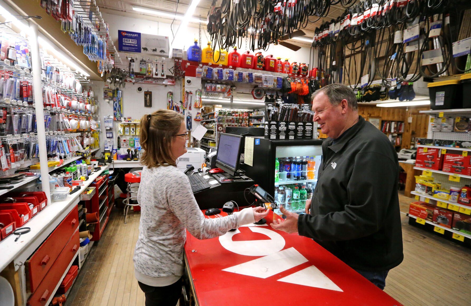 Katie Bunge (left) rings up a battery for customer Chuck Raisbeck, of Bloomington, Wis., at Hermsen