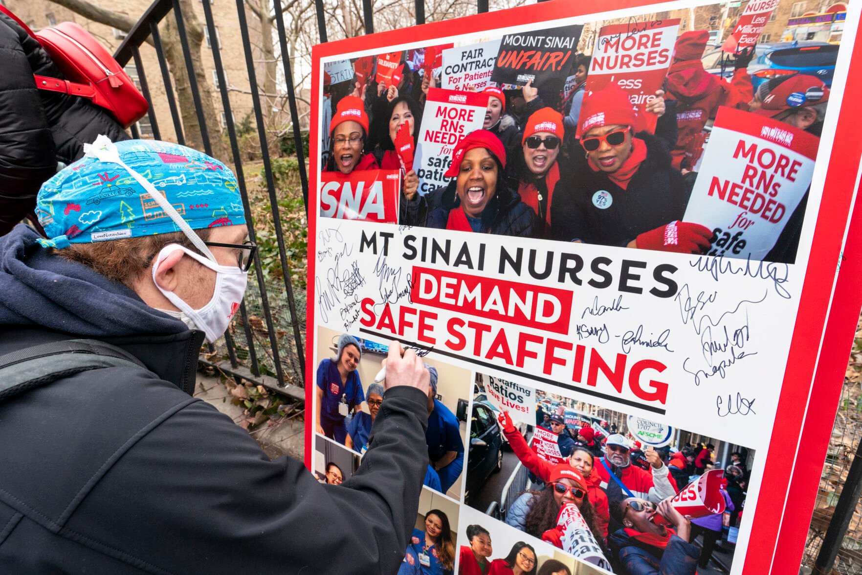 <p>FILE - Zach Clapp, a nurse in the Pediatric Cardiac ICU at Mount Sinai Hospital, signs a board demanding safe staffing during a rally by NYSNA nurses from NY Presbyterian and Mount Sinai, March 16, 2021, in New York. With a strike deadline looming, contract negotiations continued Sunday, Jan. 8, 2023, between three New York City hospitals and the union representing nearly 9,000 nurses prepared to walk out on Monday, Jan. 9, union officials said. (AP Photo/Mary Altaffer, File)</p>   PHOTO CREDIT: Mary Altaffer 