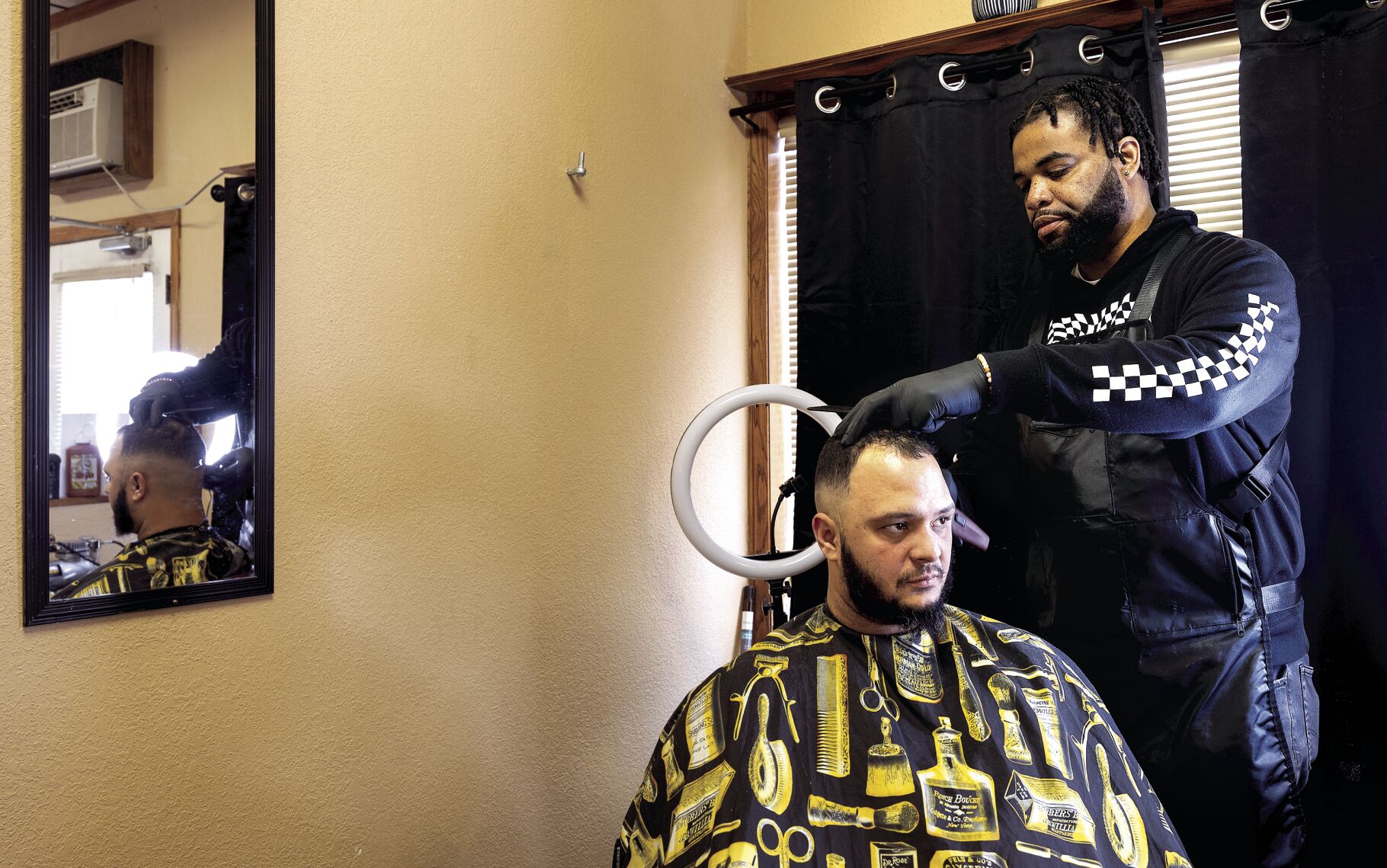 Tight Fade Barbershop owner Derrick Clark cuts the hair of Yunel Henriquez, of East Dubuque, Ill., at his barbershop on White Street in Dubuque on Friday.    PHOTO CREDIT: Stephen Gassman