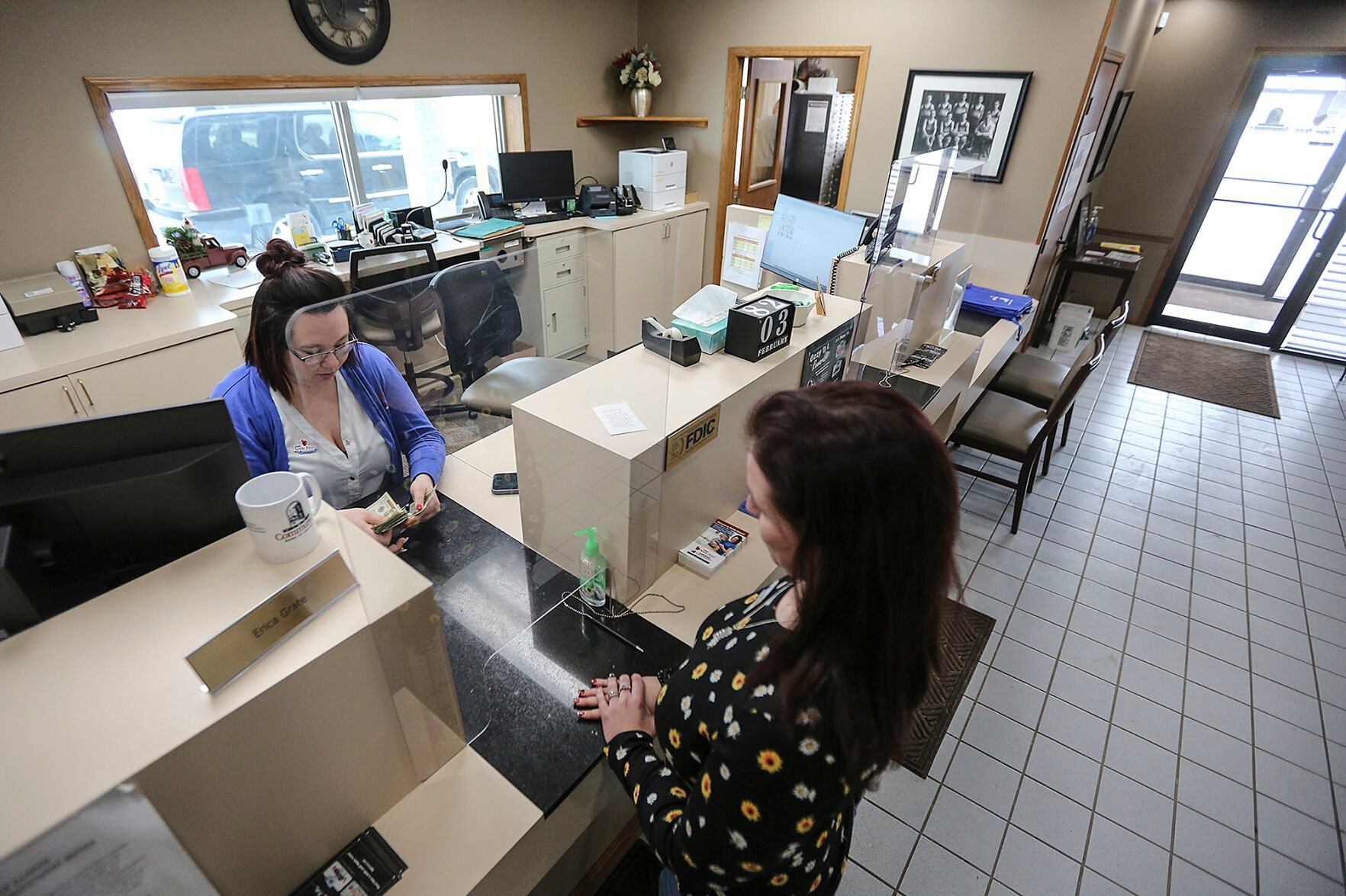 Apple River State Bank teller Erica Grate (left) works with a customer at the Hazel Green, Wis., location Friday. This year marks the bank
