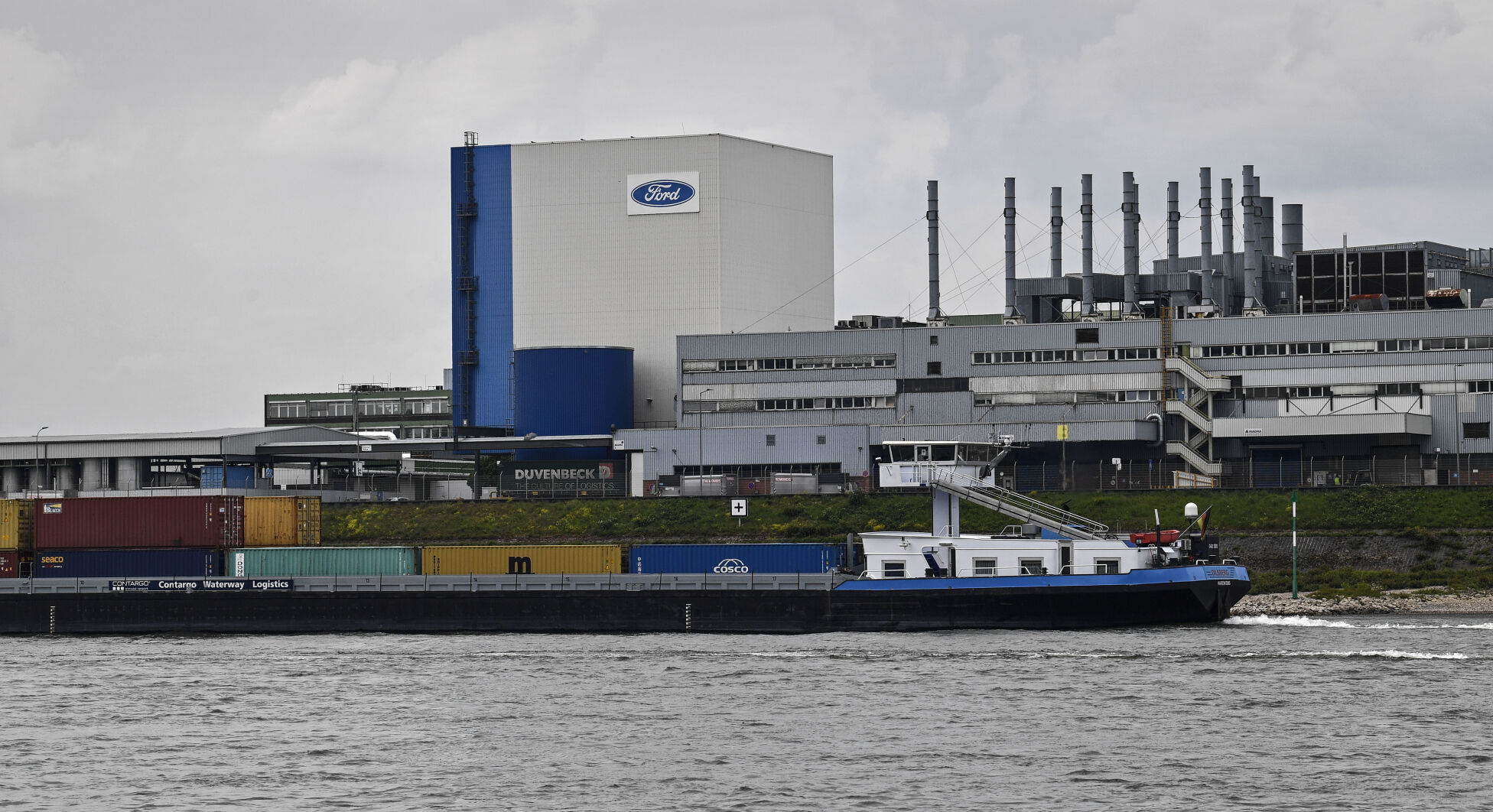 <p>FILE - A container ship passes the Ford car plant in Cologne, Germany, May 4, 2020. Ford said that it will cut 3,800 jobs in Europe over the next three years in an effort to streamline its operations as it contends with economic headwinds and increasing competition on electric cars. The automaker said that 2,300 jobs will go in Germany. (AP Photo/Martin Meissner, File)</p>   PHOTO CREDIT: Martin Meissner 