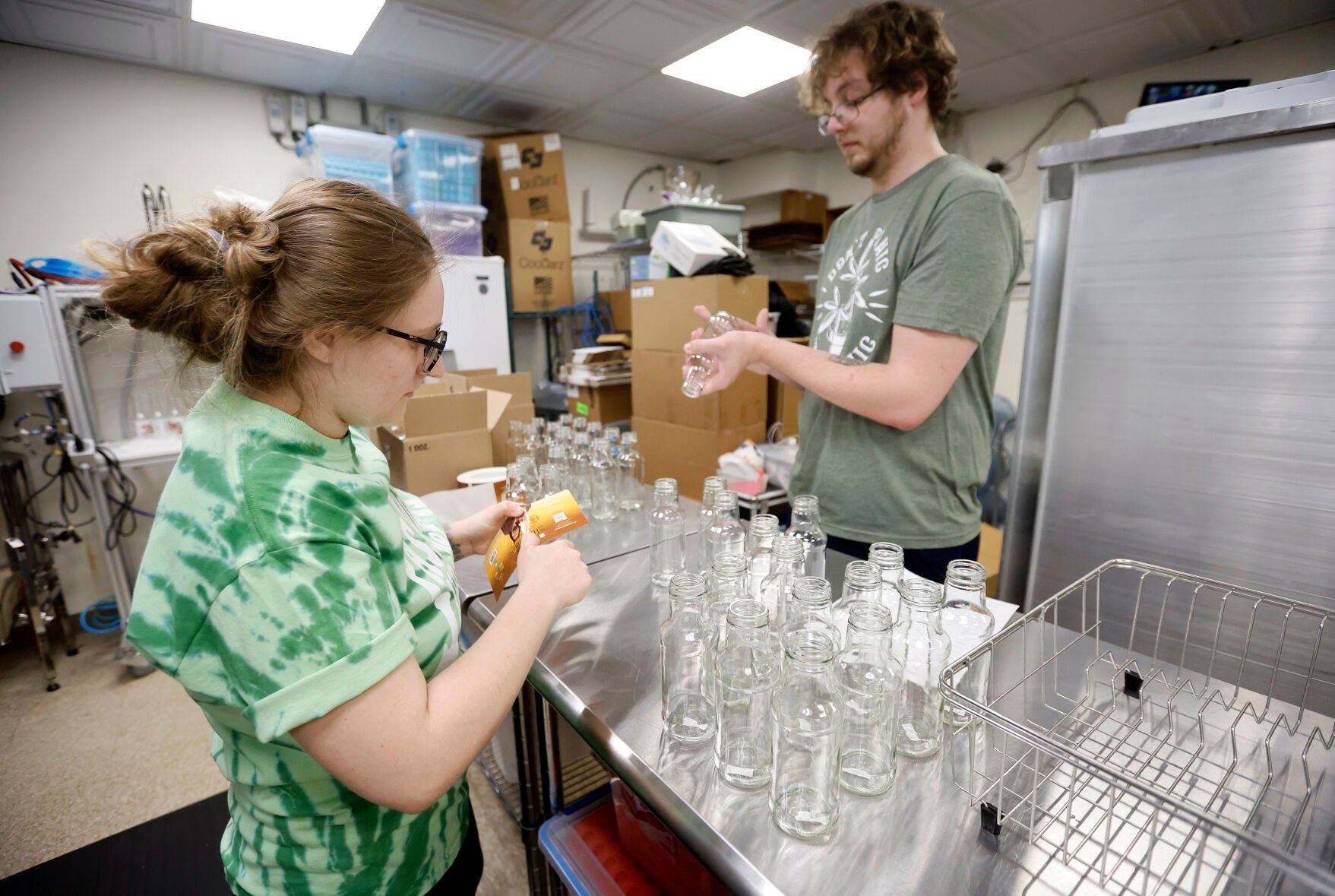 Tabitha Benson (left) and Matt Hopkins label bottles for products.    PHOTO CREDIT: JESSICA REILLY
Telegraph Herald