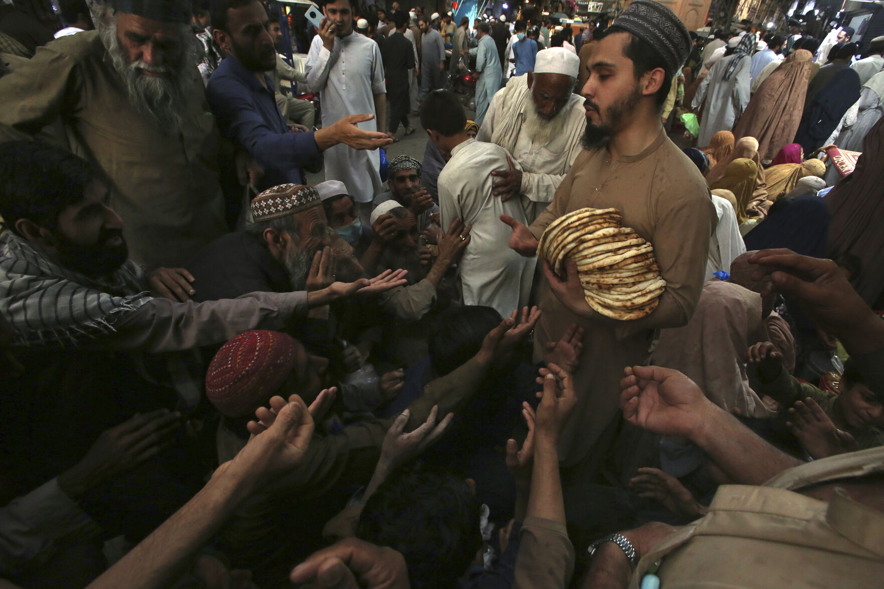 <p>A worker distributes free traditional roti or bread among needy people at a restaurant, in Peshawar, Pakistan, Sunday, April 16, 2023. People are suffering from recent price hike in food, gas, fuel, and power in Pakistan. (AP Photo/Muhammad Sajjad)</p>   PHOTO CREDIT: Muhammad Sajjad 