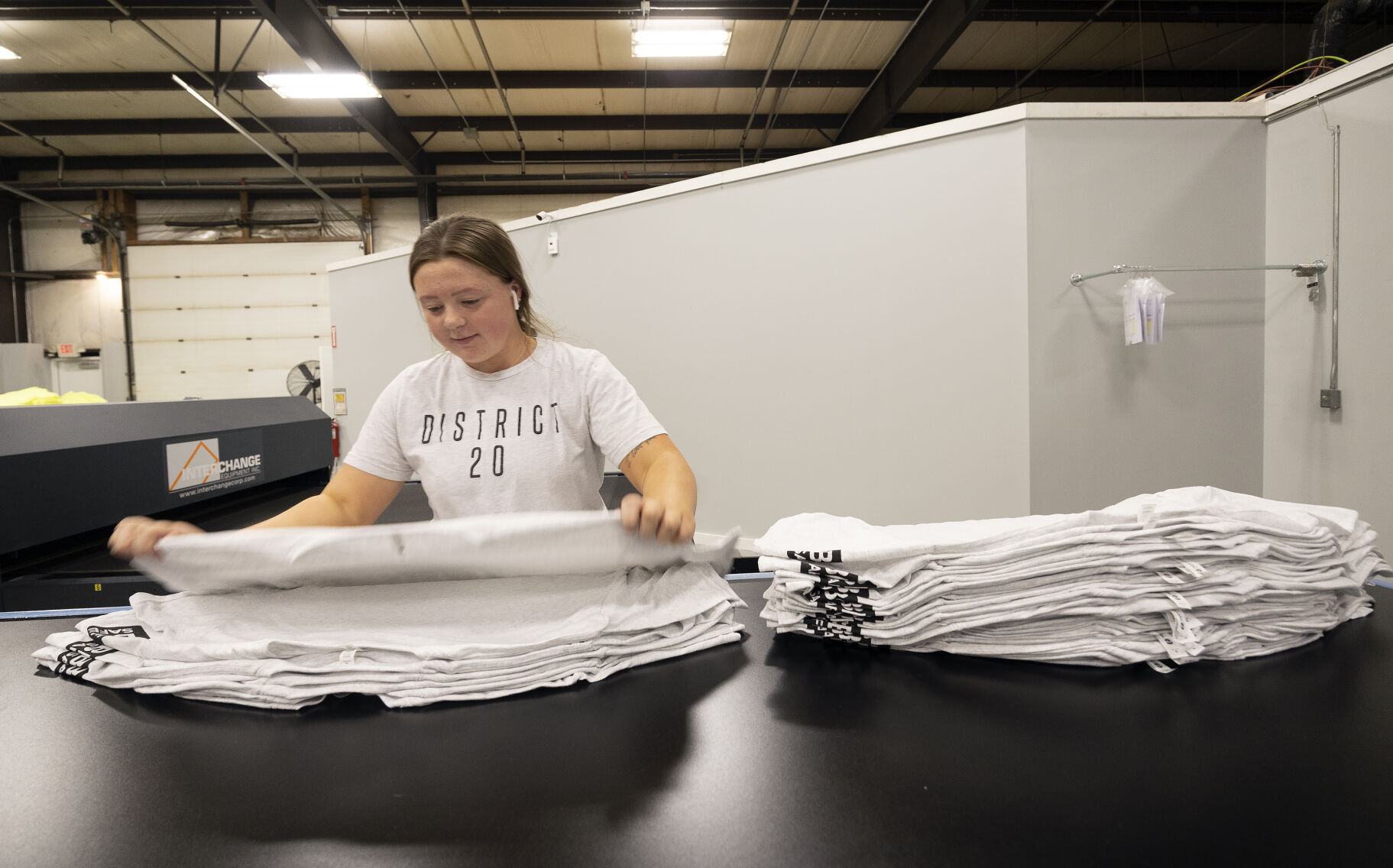 Ella Noel stacks newly screen printed shirts at District 20.    PHOTO CREDIT: Stephen Gassman