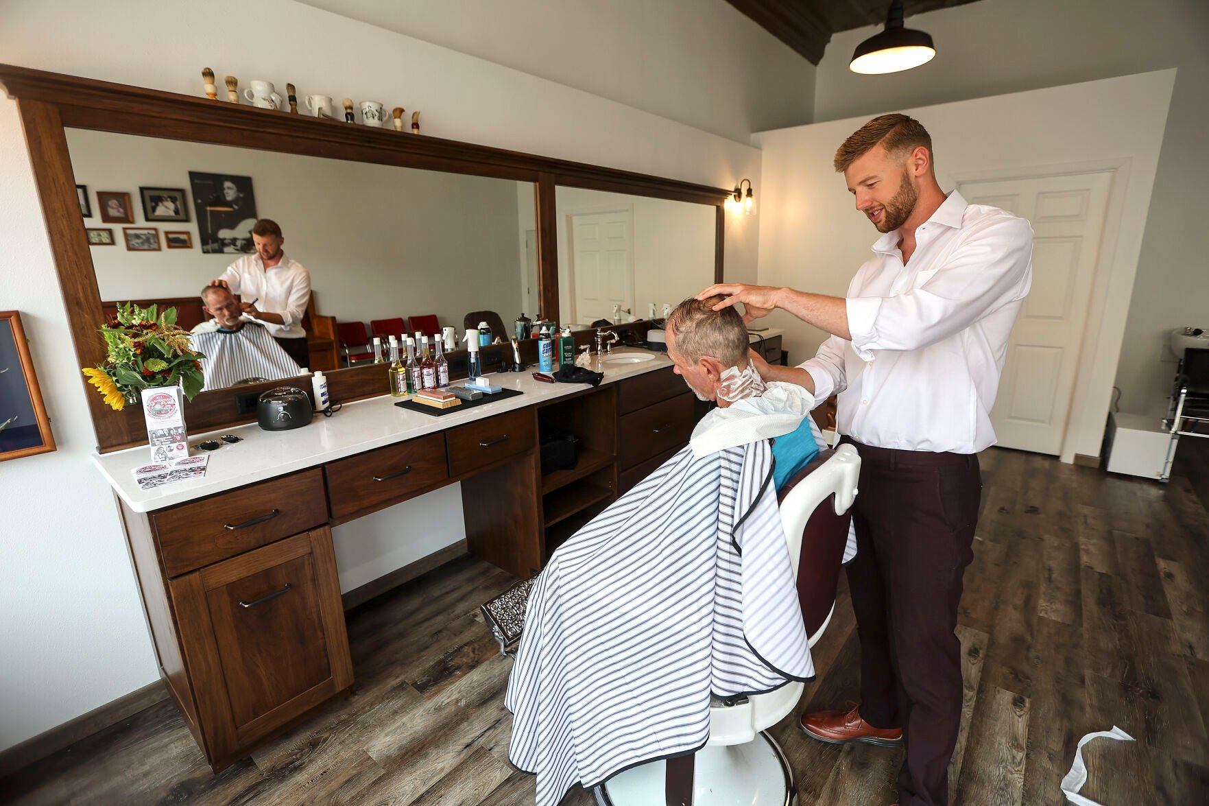 Owner of Traditions Barbershop Josh Smith works with customer Rob Kempf, of Manchester, Iowa, in his shop located at 113 East Main Street in Manchester.    PHOTO CREDIT: Dave Kettering