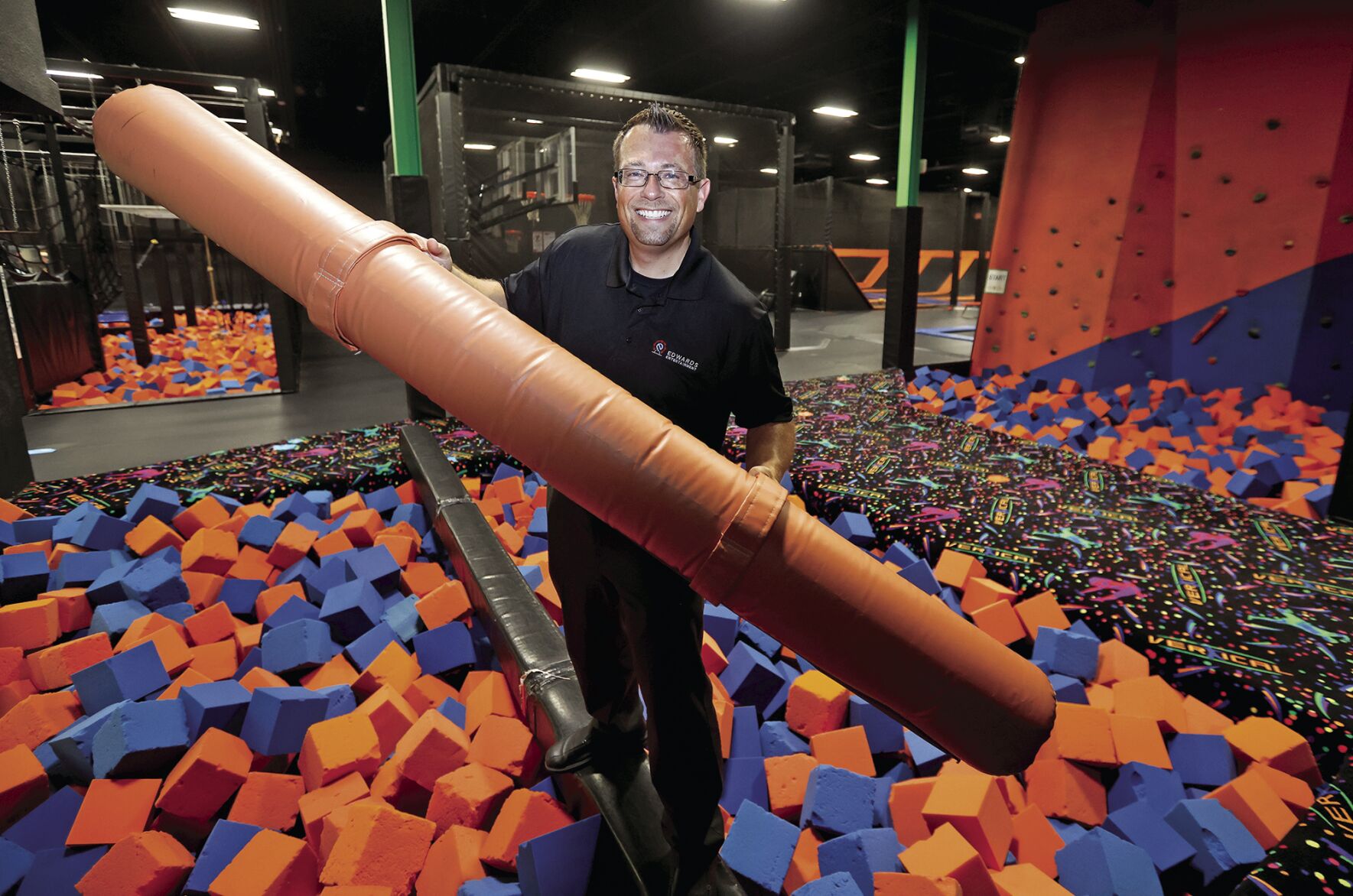 Nick Edwards, owner of The Fun Station Dubuque, holds a pugil stick inside facility at Kennedy Mall.    PHOTO CREDIT: JESSICA REILLY