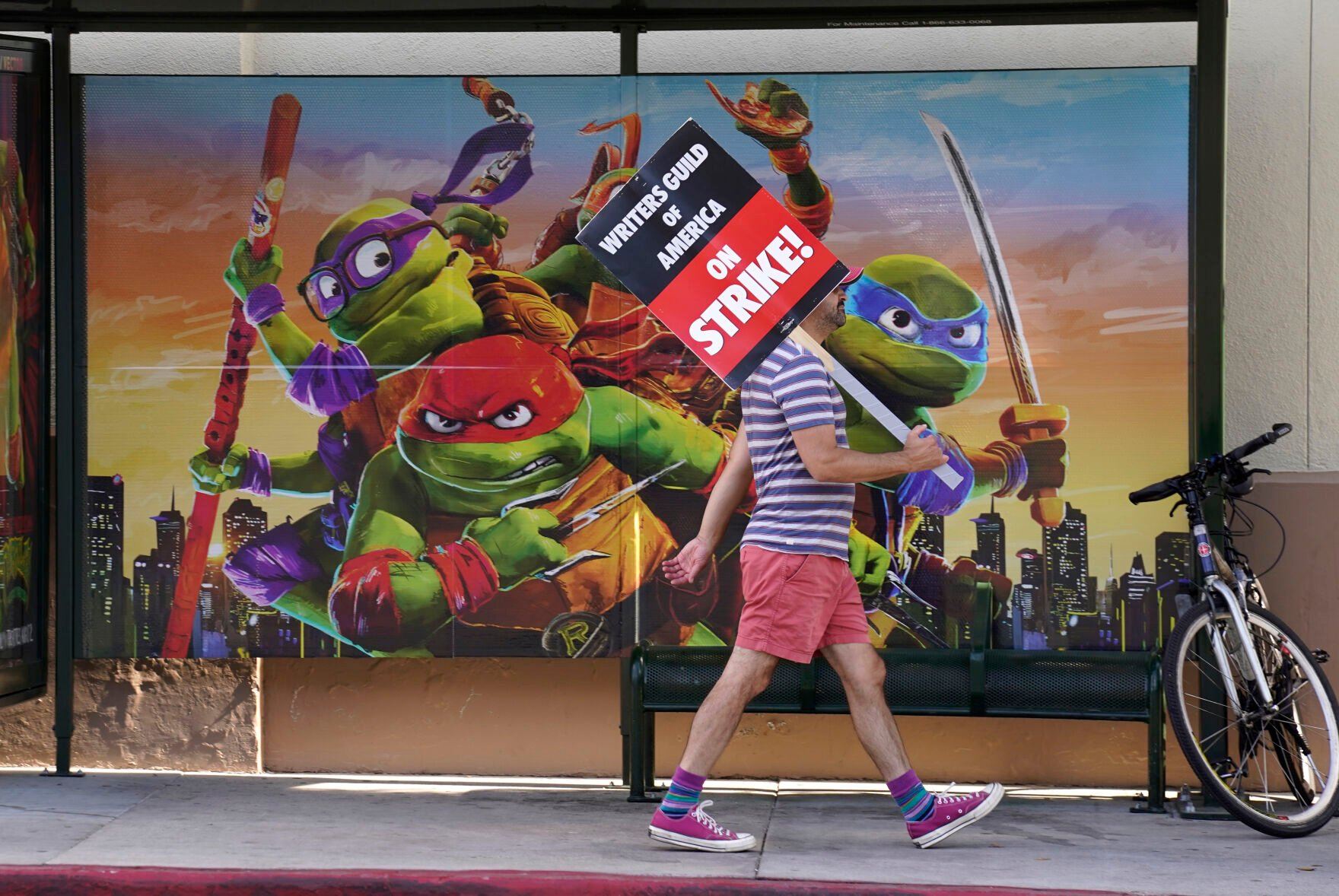 <p>A picketer walks past an advertisement for "Teenage Mutant Ninja Turtles: Mutant Mayhem" outside Paramount studios on Wednesday, July 26, 2023, in Los Angeles. The actors strike comes more than two months after screenwriters began striking in their bid to get better pay and working conditions. (AP Photo/Chris Pizzello)</p>   PHOTO CREDIT: Chris Pizzello 