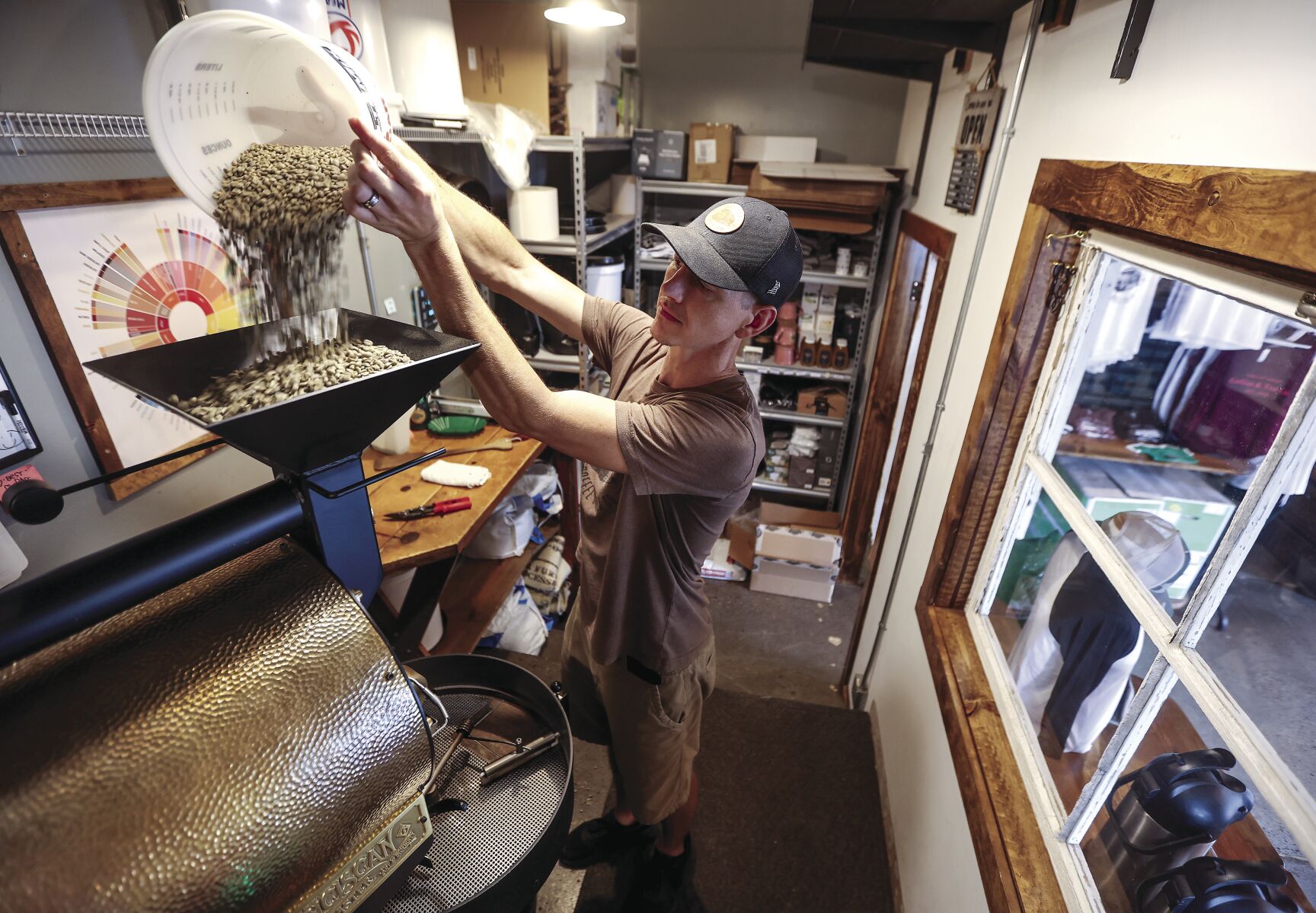 Corey Heller, co-owner of Trolley Depot Coffee & Tea Co. in Galena, Ill., pours coffee beans into a roaster.    PHOTO CREDIT: Dave Kettering