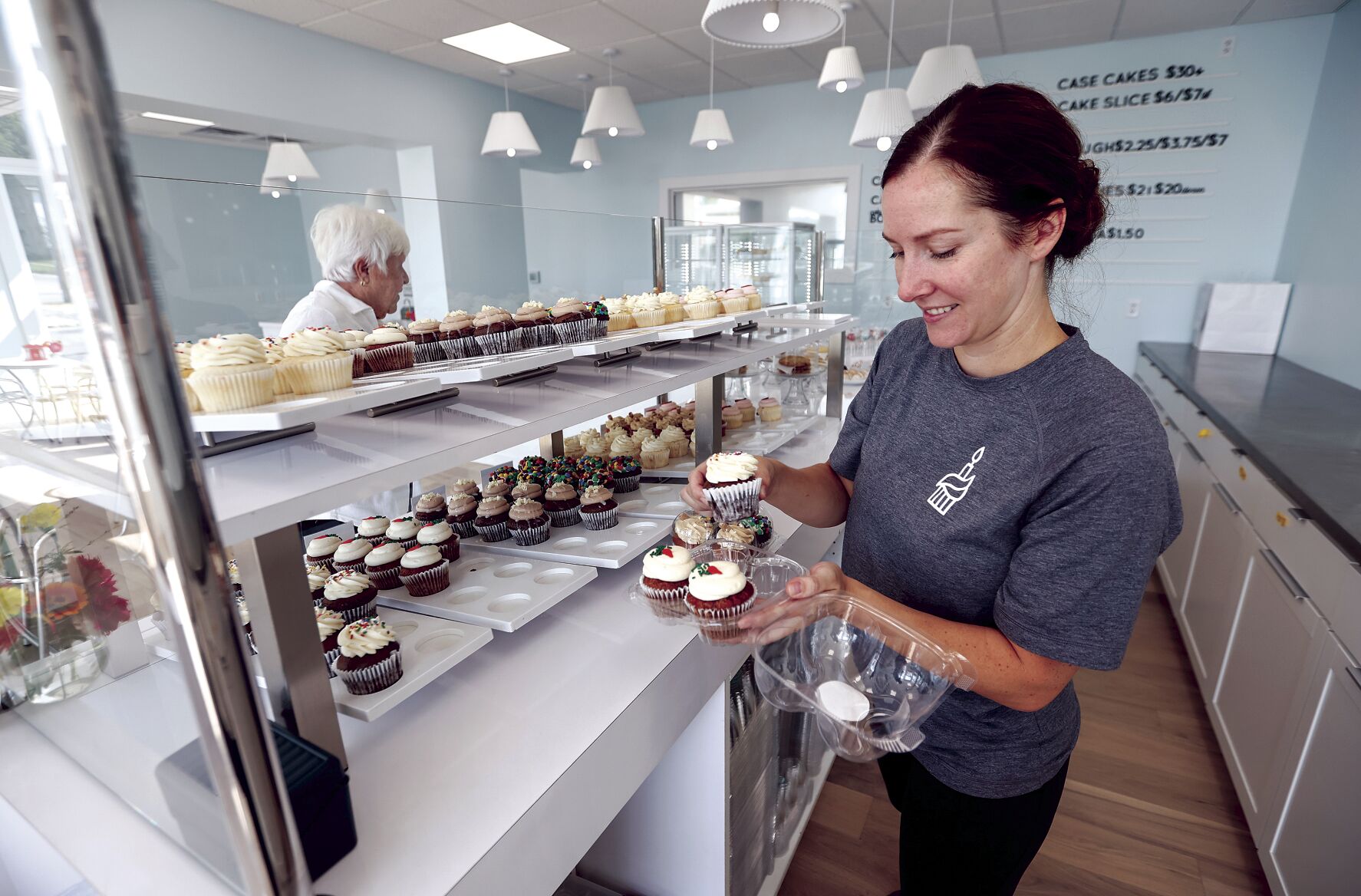 Jill Takosky packages cupcakes for Shirley Cardy, of Dubuque, at Candle Ready Cakes in Dubuque on Tuesday. The business has moved to its new, larger location at 249 W. First St.    PHOTO CREDIT: JESSICA REILLY