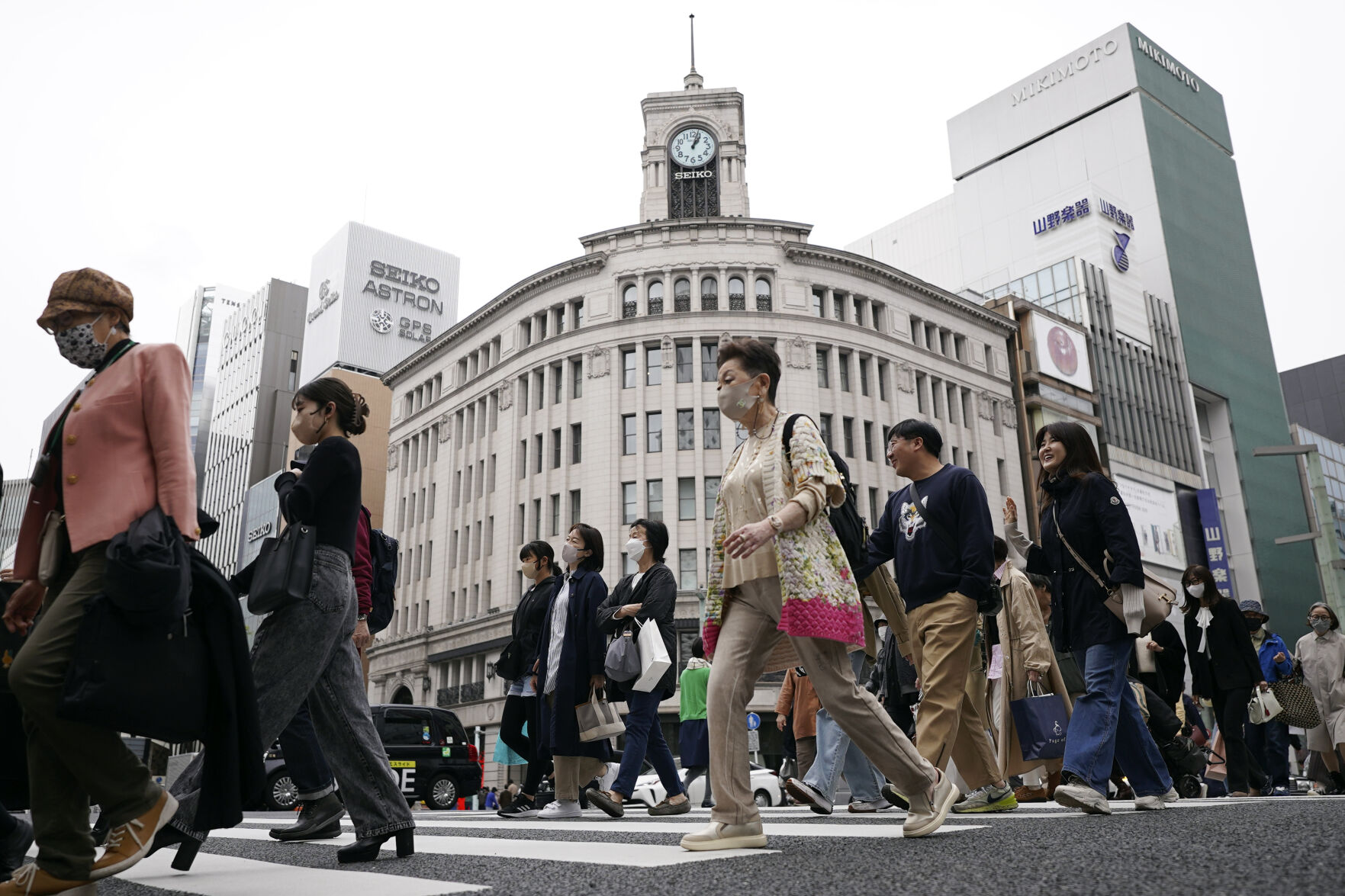 <p>FILE - People walk across a pedestrian crossing in Ginza shopping district on March 31, 2023, in Tokyo. Business sentiment among big Japanese manufacturers improved in July-September for the second straight quarter, according to a central bank survey released Monday, Oct 2. (AP Photo/Eugene Hoshiko, File)</p>   PHOTO CREDIT: Eugene Hoshiko 