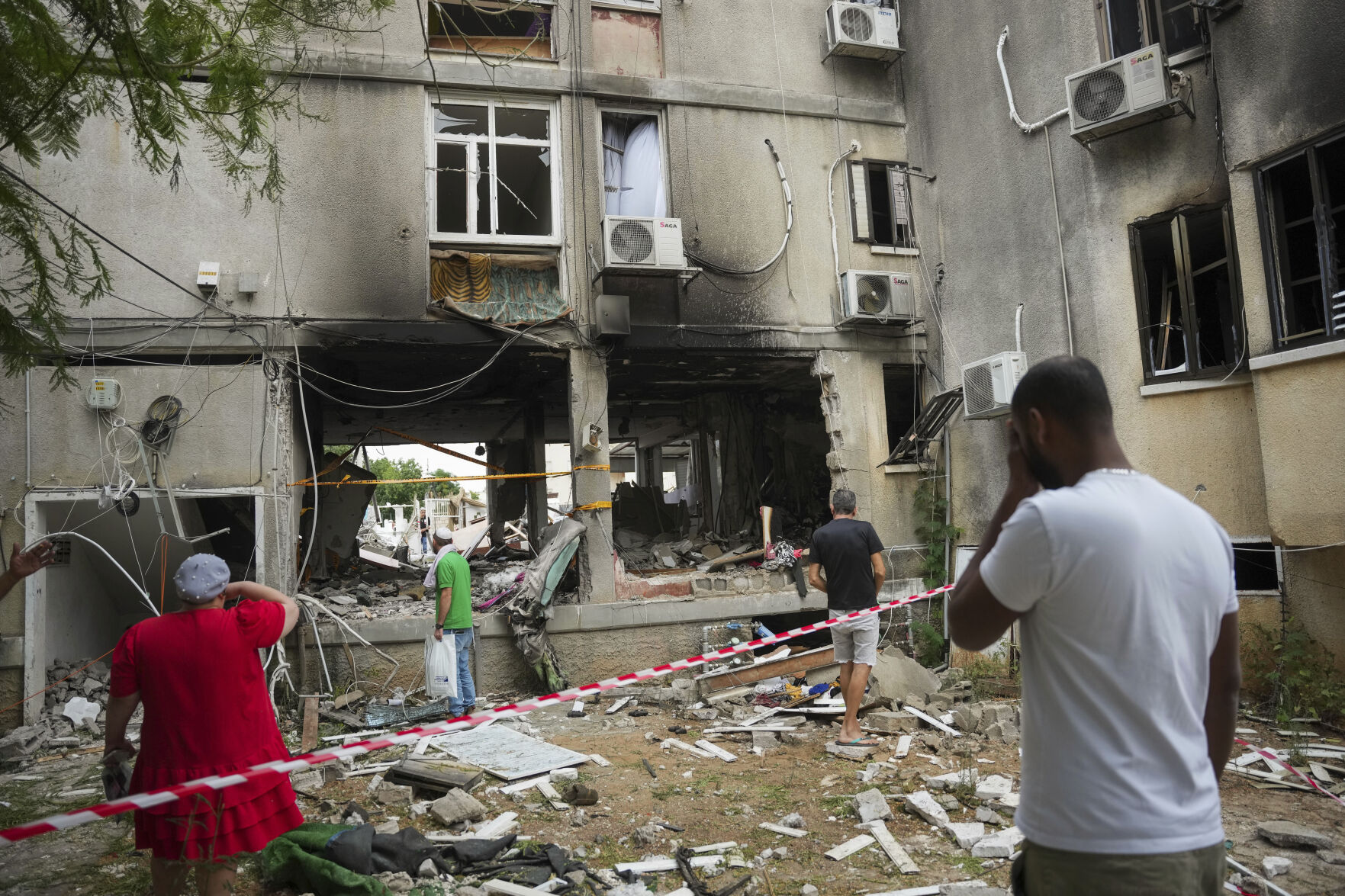 <p>Israelis inspect a damaged residential building after it was hit by a rocket fired from the Gaza Strip, in Ashkelon, Israel, Monday, Oct. 9, 2023. The militant Hamas rulers of the Gaza Strip carried out an unprecedented, multi-front attack on Israel at daybreak Saturday, firing thousands of rockets as dozens of Hamas fighters infiltrated the heavily fortified border in several locations by air, land, and sea, killing hundreds and taking captives. Palestinian health officials reported scores of deaths from Israeli airstrikes in Gaza. (AP Photo/Erik Marmor)</p>   PHOTO CREDIT: Erik Marmor - stringer, ASSOCIATED PRESS