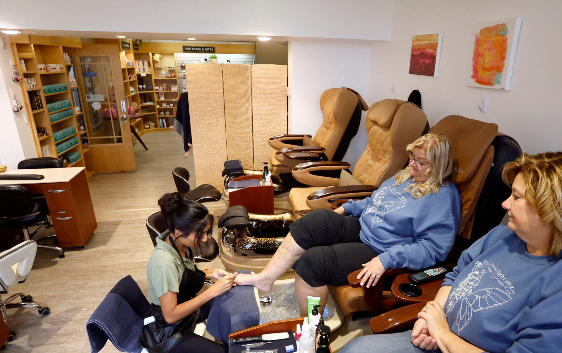 Laura Fernandes (left), a cosmetologist at Body & Soul Wellness Center and Spa, gives pedicures to Lisa Harmon (middle), of Otter Creek, Iowa, and Jan Gill, of Dubuque.    PHOTO CREDIT: Jessica Reilly