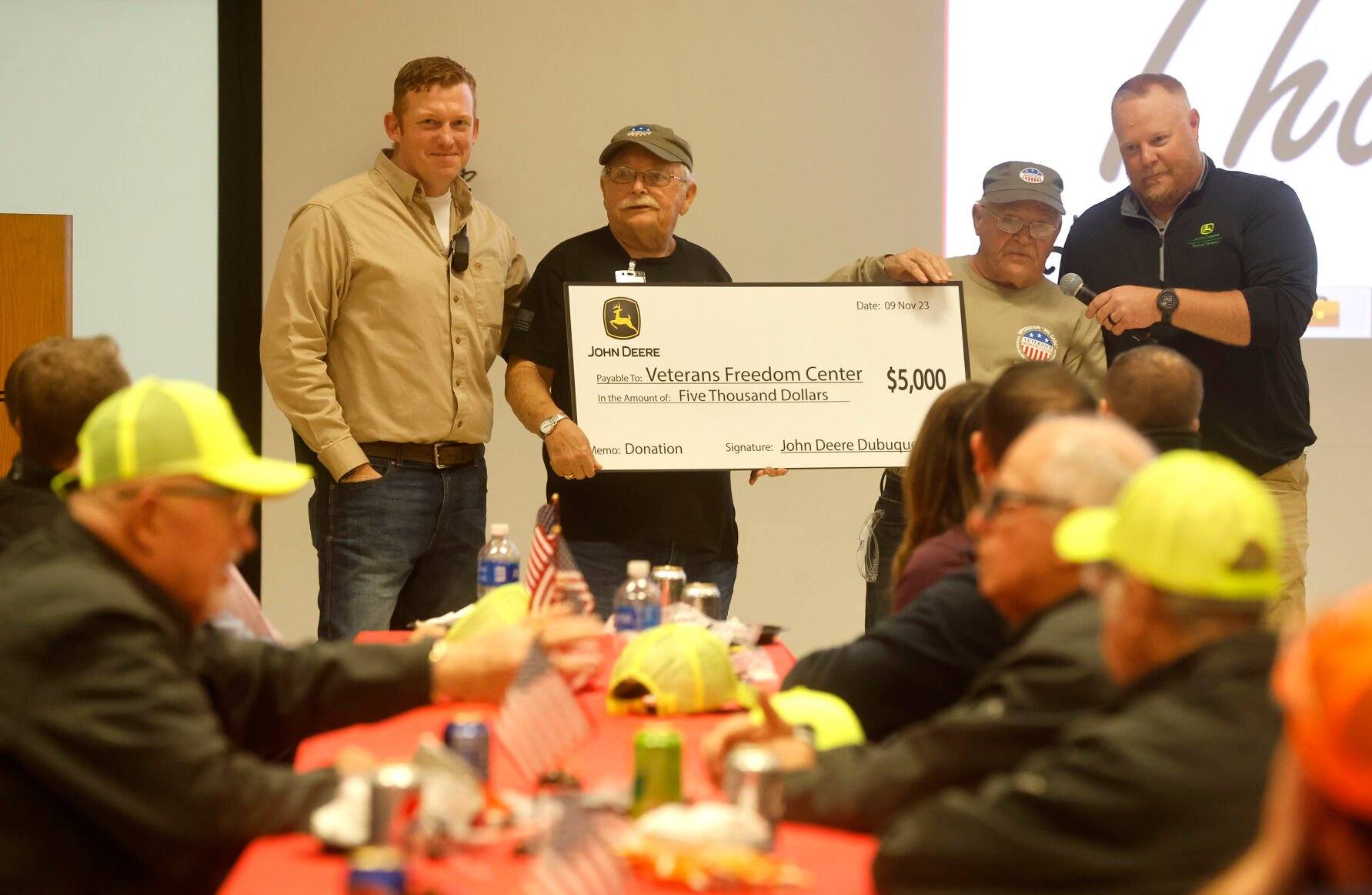 Alec Zwanziger (far left) and Dan Kerkhoff (far right), both with John Deere Dubuque Works, present Jim Wagner (second from left) and Allan Rowell, both with Veterans Freedom Center, a check during a Veterans Day luncheon recognizing employee veterans at the facility in Dubuque on Thursday, Nov. 9, 2023.    PHOTO CREDIT: JESSICA REILLY