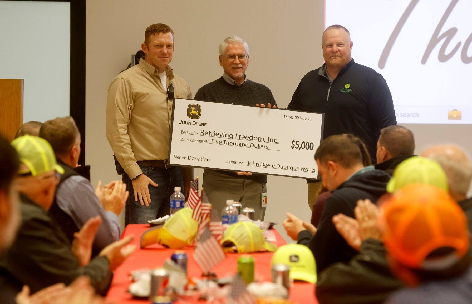 Alec Zwanziger (far left) and Dan Kerkhoff (far right), both with John Deere Dubuque Works, present Calvin Ver Mulm, with Retrieving Freedom, a check during a Veterans Day luncheon recognizing employee veterans at the facility in Dubuque on Thursday, Nov. 9, 2023.    PHOTO CREDIT: JESSICA REILLY