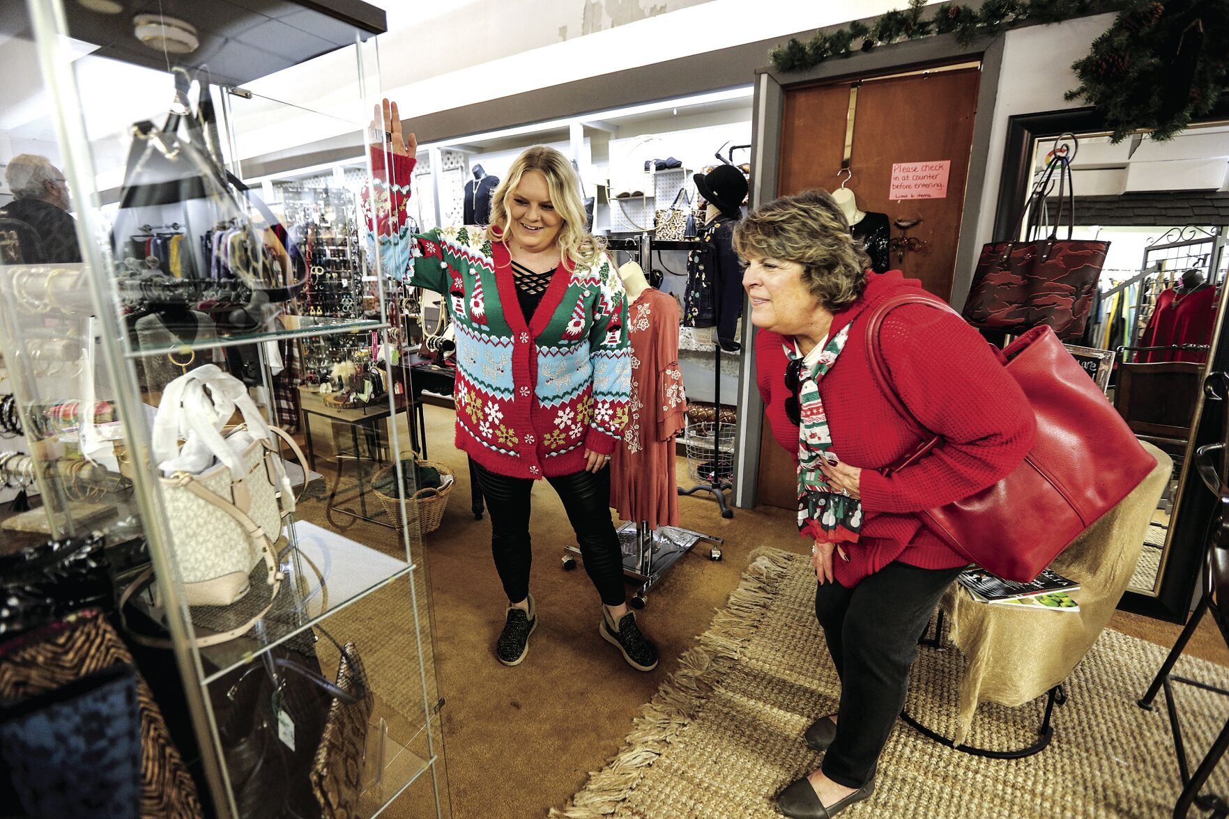 Gabrielle Soppe (left), Owner of Repeats Consignment, shows LaDawn Hankins, of Waterloo, Iowa, some of the purses for sale at the store in Manchester, Iowa, on Thursday.    PHOTO CREDIT: Dave Kettering