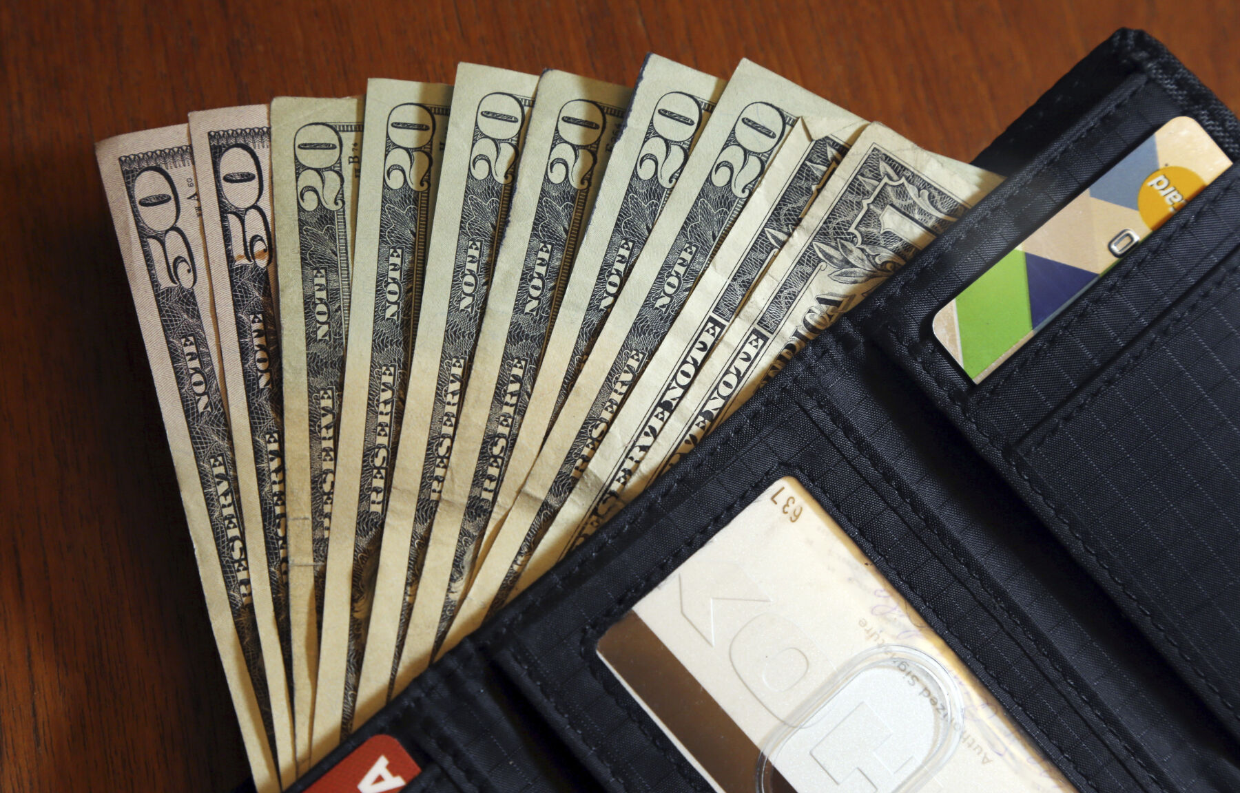 FILE - In this June 15, 2018, file photo, cash is fanned out from a wallet in North Andover, Mass. As you plan your holiday giving, you may be thinking about adding service workers to your list of recipients. (AP Photo/Elise Amendola, File)    PHOTO CREDIT: Associated Press