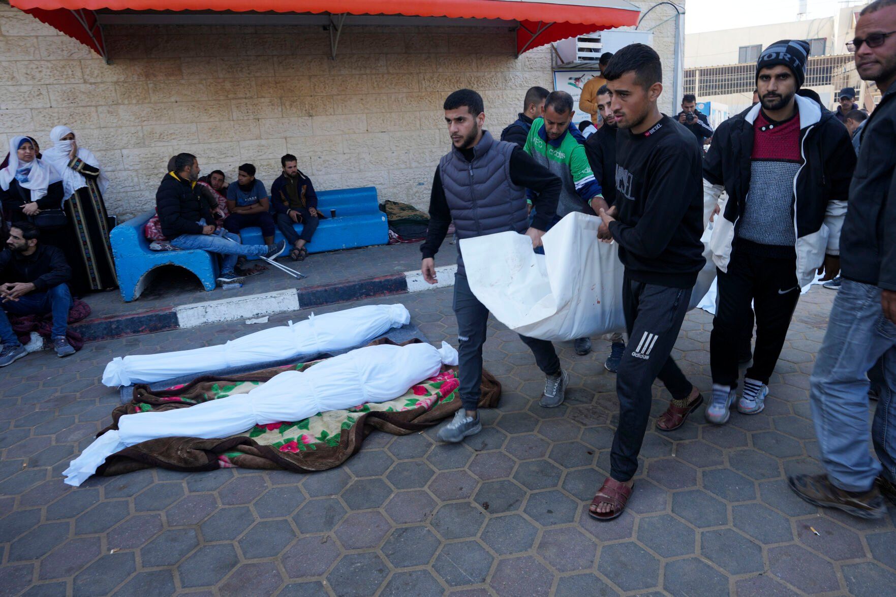 <p>Palestinians carry a relative killed in the Israeli bombardment of the Gaza Strip, in front of the morgue at the hospital in Deir al Balah, Gaza Strip, Monday, Dec. 18, 2023. (AP Photo/Adel Hana)</p>   PHOTO CREDIT: Adel Hana 