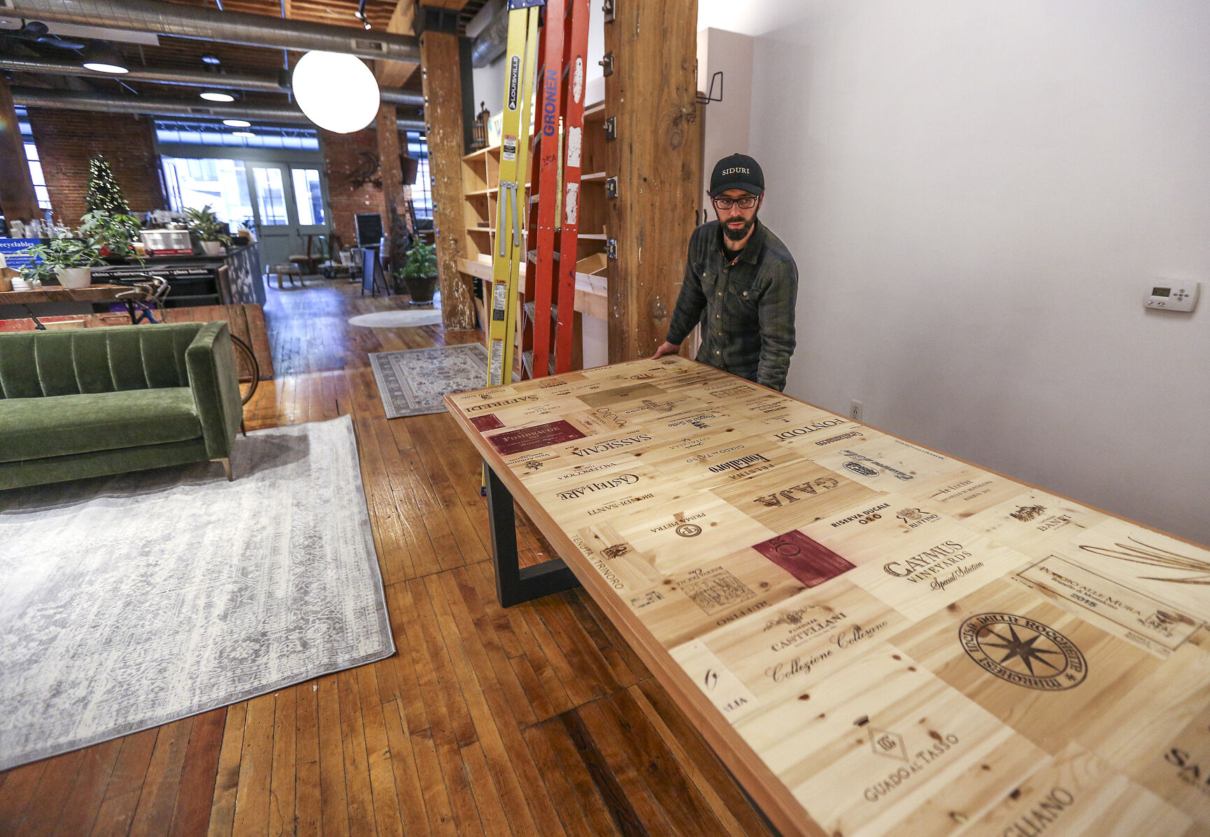 E.J. Droessler moves a custom made table into position while working on his new business, E.J.’s Wine Shop & Tasting Room located in the Millwork District in the space previously occupied by Inspire Cafe. The business will share space with Wayfarer Coffee.    PHOTO CREDIT: Dave Kettering