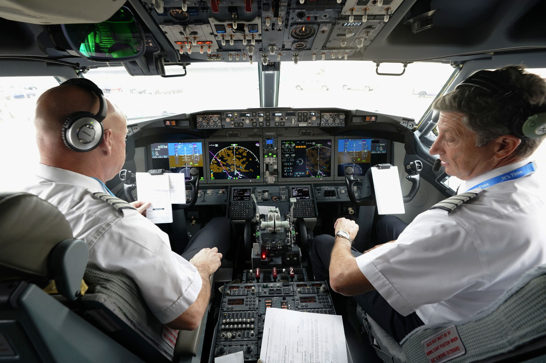 FILE - American Airlines pilot captain Pete Gamble, left, and first officer John Konstanzer conduct a pre-flight check before taking off from Dallas Fort Worth airport on Dec. 2, 2020, in Grapevine, Texas. The Federal Aviation Administration is warning against raising the mandatory retirement age for airline pilots. The FAA says it needs to study the safety implications before raising the age. FAA Administrator Mike Whitaker told key senators about the agency