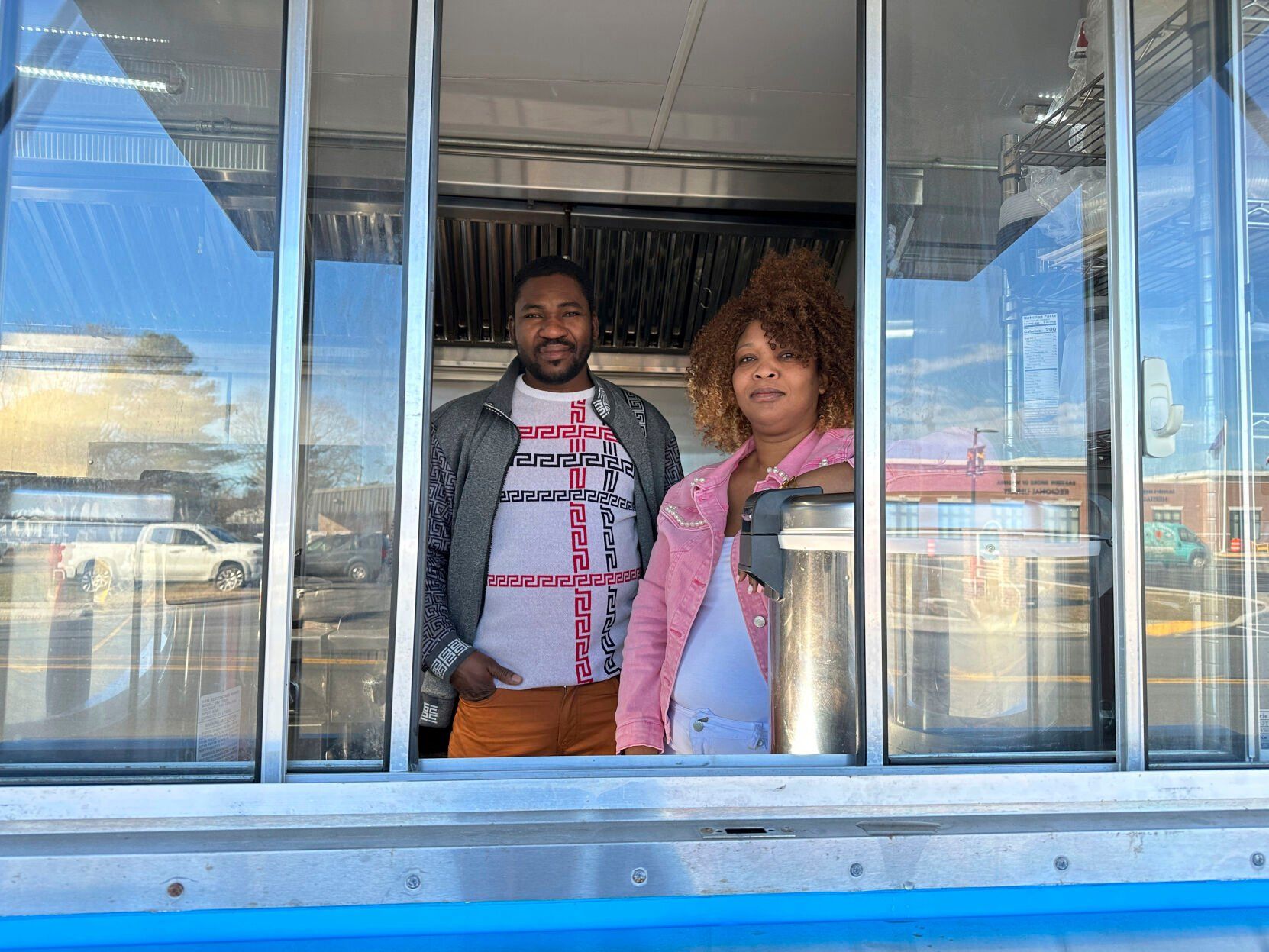Theslet Benoir and Clemene Bastien stand at the window of their Eben-Ezer Haitian food truck in Parksley, Va., on Wednesday, Jan. 24, 2024. The married couple is suing the town in federal court over allegations that their food truck was forced to close. The couple also says a town councilman cut the mobile kitchen