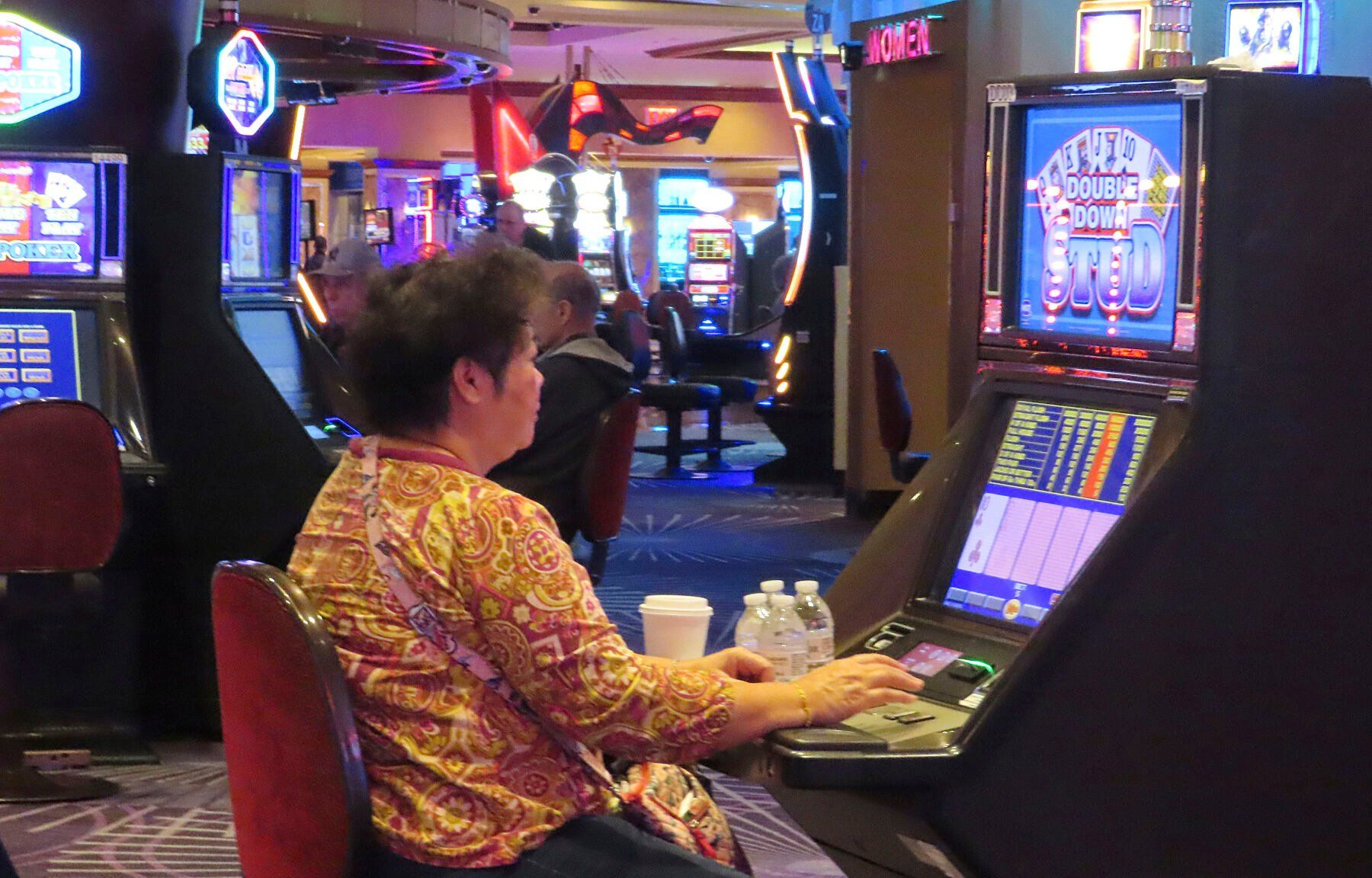 A gambler plays a slot machine at Harrah