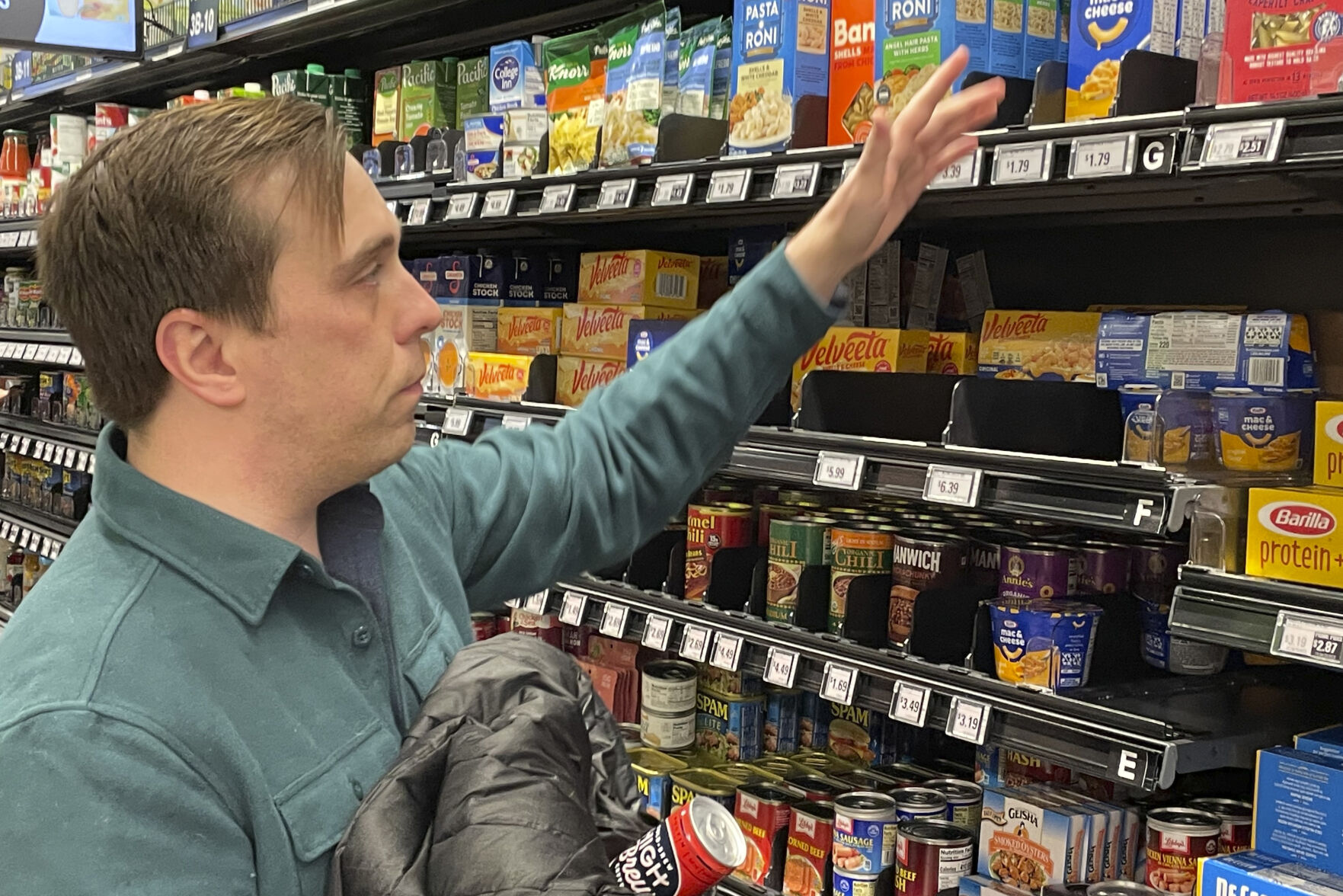 <p>Stuart Dryden reaches for an item at a grocery store on Wednesday, Feb. 21, 2024, in Arlington, Va. Dryden is aware of big price disparities between branded products and their store-label competitors, which he now favors. (AP Photo/Chris Rugaber)</p>   PHOTO CREDIT: Chris Rugaber 