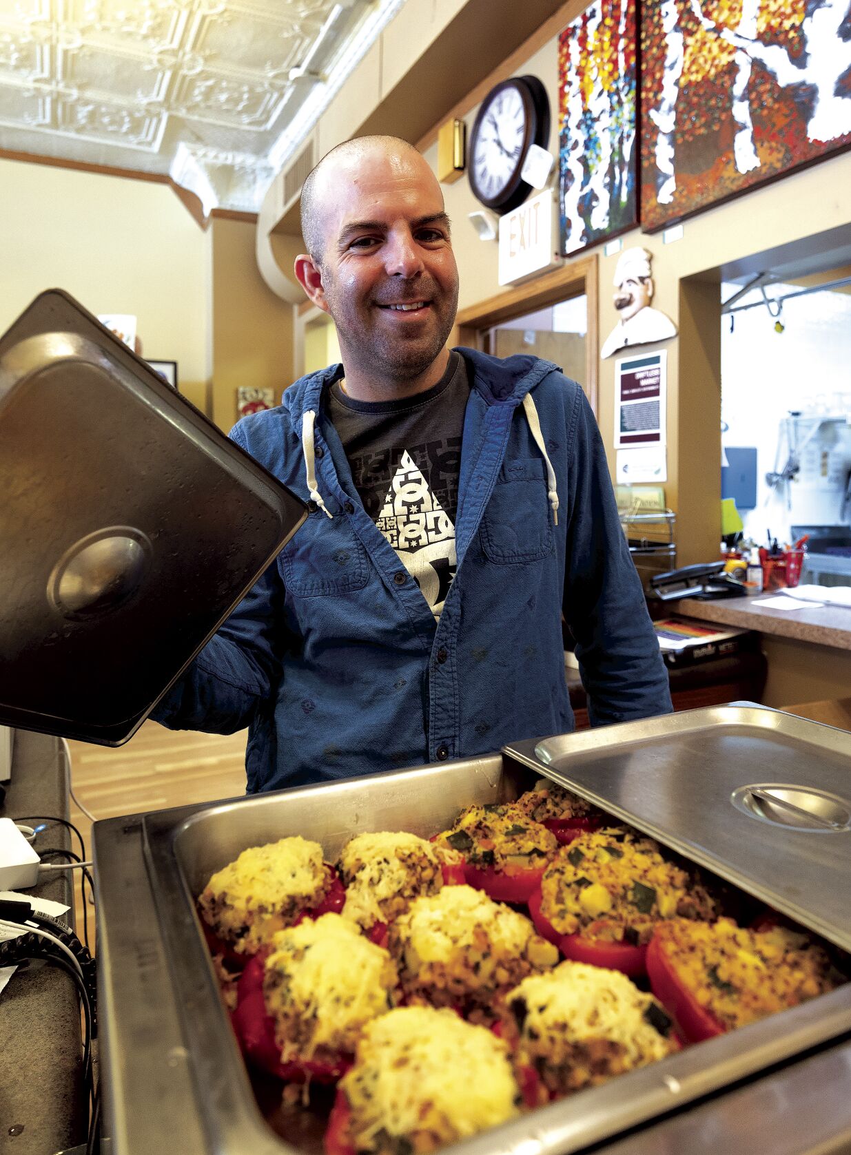 Store manager Nate Robinson shows off the stuffed peppers being served at Driftless Market. Imperfect-looking produce has been redirected from the store’s shelves to its deli to minimize food waste.    PHOTO CREDIT: Stephen Gassman