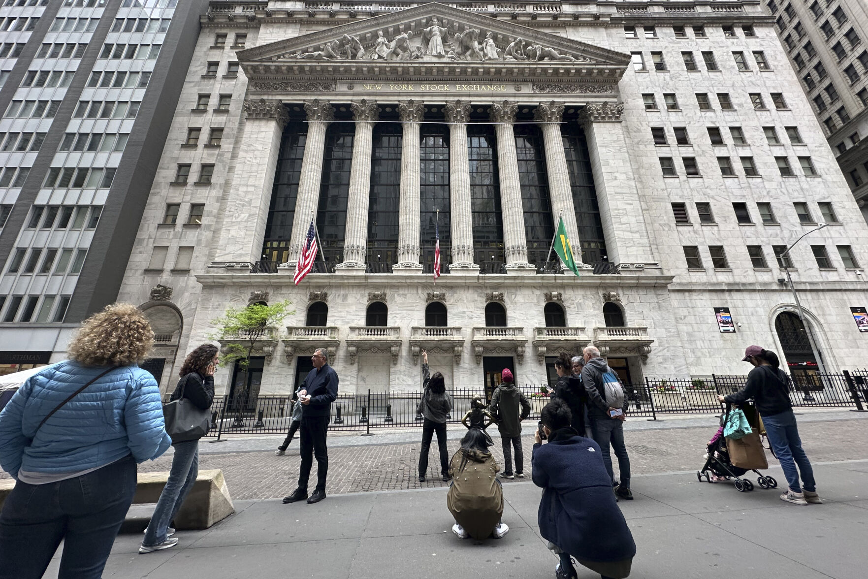 <p>FILE - Tourists gather near the New York Stock Exchange on May 16, 2024, in New York. Shares retreated in Europe and Asia on Friday, May 24, 2024, after unexpectedly strong reports on the U.S. economy raised the possibility that interest rates may stay painfully high. (AP Photo/Peter Morgan, File)</p>   PHOTO CREDIT: Peter Morgan - staff, ASSOCIATED PRESS