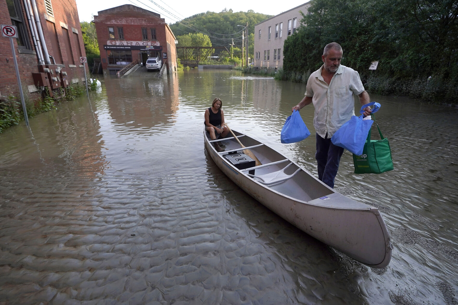 <p>FILE - Jodi Kelly, seated center, practice manager at Stonecliff Veterinary Surgical Center, behind, and her husband Veterinarian Dan Kelly, right, use a canoe to remove surgical supplies from the flood damaged center, Tuesday, July 11, 2023, in Montpelier, Vt. Vermont has become the first state to enact a law requiring fossil fuel companies to pay a share of the damage caused by climate change, Thursday, May 30, 2024 after the state suffered catastrophic summer flooding and damage from other extreme weather. (AP Photo/Steven Senne, File)</p>   PHOTO CREDIT: Steven Senne - staff, ASSOCIATED PRESS