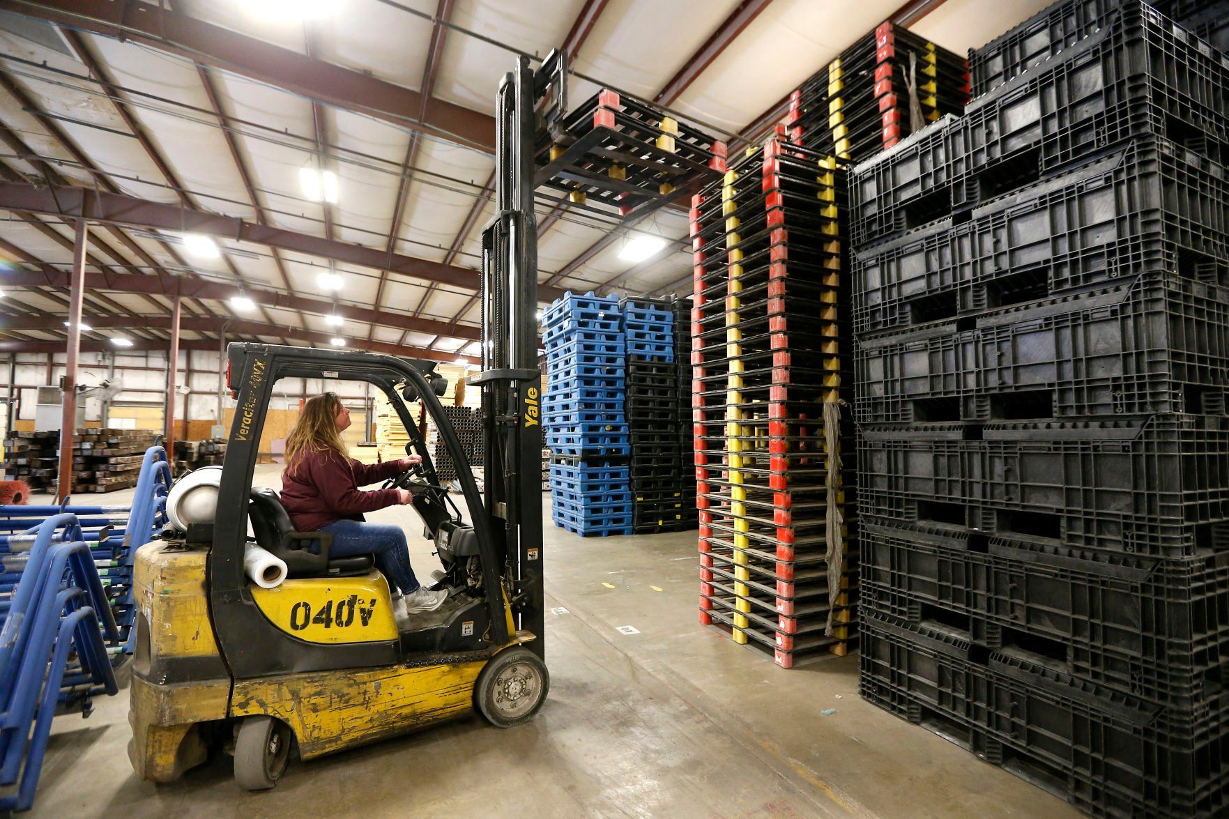 Jessi Walker, manager of Repurposed Materials in Maquoketa, Iowa, stacks up flat pallets that are among the many items for sale at the business.    PHOTO CREDIT: Dave Kettering
Telegraph Herald