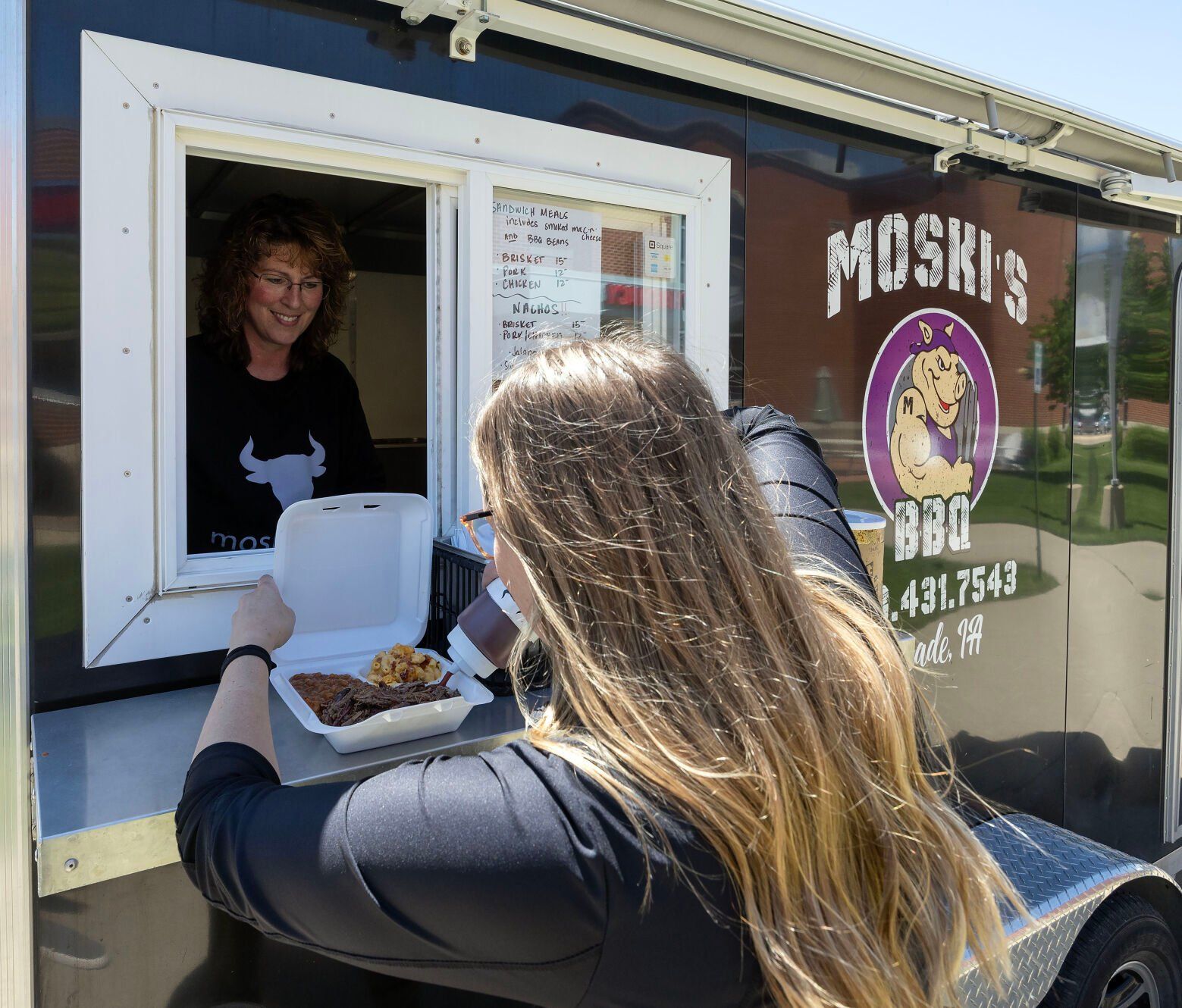 Staci Fritz watches as Justice Damm adds sauce to her sandwich.    PHOTO CREDIT: Gassman