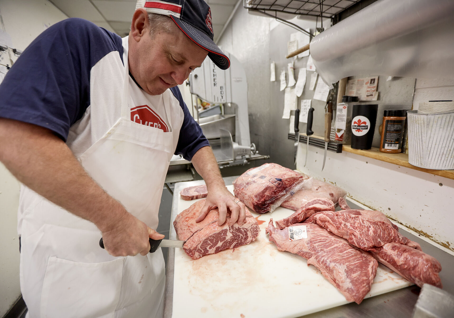 Jeff Cremer, of Cremer’s Grocery, slices steaks at his family-owned business. Cremer said when looking for a good-quality steak, “fat is flavor, and flavor is fat.”    PHOTO CREDIT: Dave Kettering/Telegraph Herald