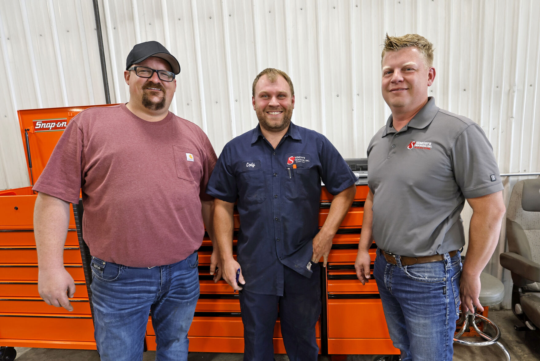 Owners RJ Simon (left) and Justin Philipp (right) stand with employee Cody Olson at Simon’s Trucking.    PHOTO CREDIT: File photo