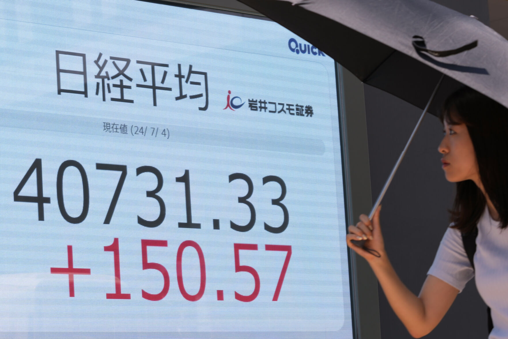 A passerby walks past an electronic stock board showing Japan