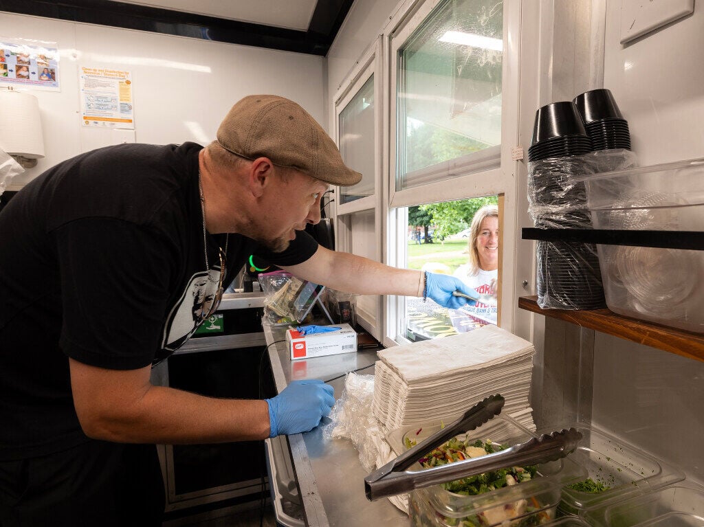 Joshua Roberts, director of food and beverage, hands change back to a customer inside Frank O’Dowds food truck parked at Washington Square in Dubuque on Friday. 