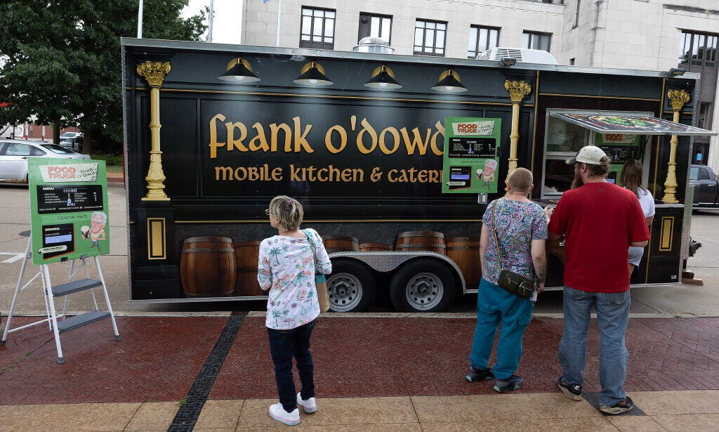 Customers wait in line at Frank O’Dowd’s food truck parked at Washington Square in Dubuque on Friday. 