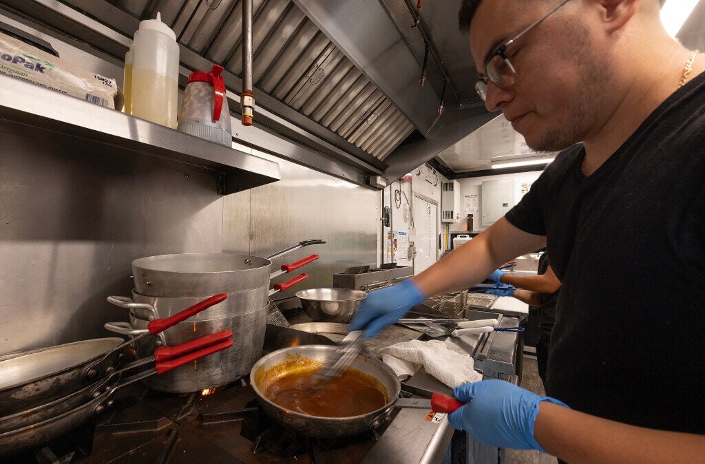 Froy Cruz, executive chef, prepares a sauce on the stove inside Frank O’Dowd’s food truck parked at Washington Square in Dubuque on Friday. 