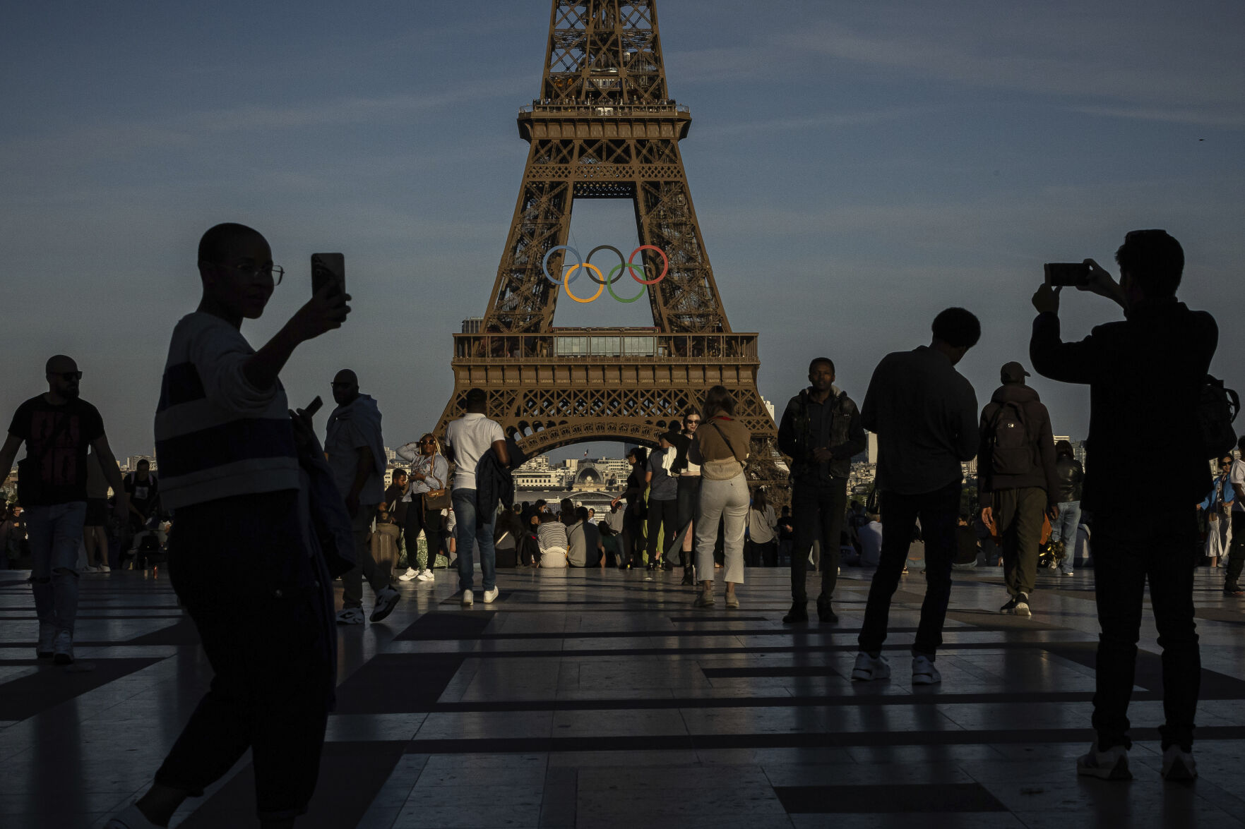 <p>FILE - People use their smartphones near the Olympic rings that are displayed on the Eiffel Tower in Paris, June 7, 2024 in Paris. Cybersecurity experts and French officials say Russian disinformation campaigns against France are zeroing in on legislative elections and the Olympic Games which open in Paris at the end of the month. (AP Photo/Aurelien Morissard, File)</p>   PHOTO CREDIT: Aurelien Morissard 