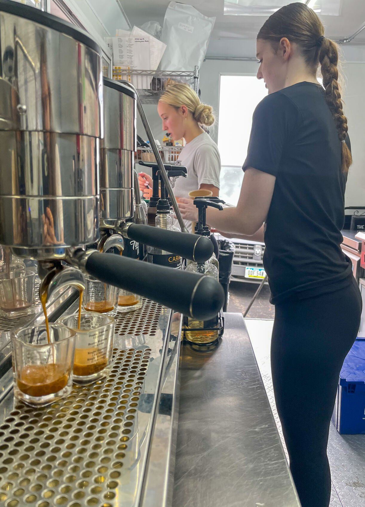 Jayme Frank (left) and Sydney Hall prepare customers’ orders in the Galena Roasters coffee truck at The Galena Territory Farmers Market.    PHOTO CREDIT: Elizabeth Kelsey
Telegraph Herald